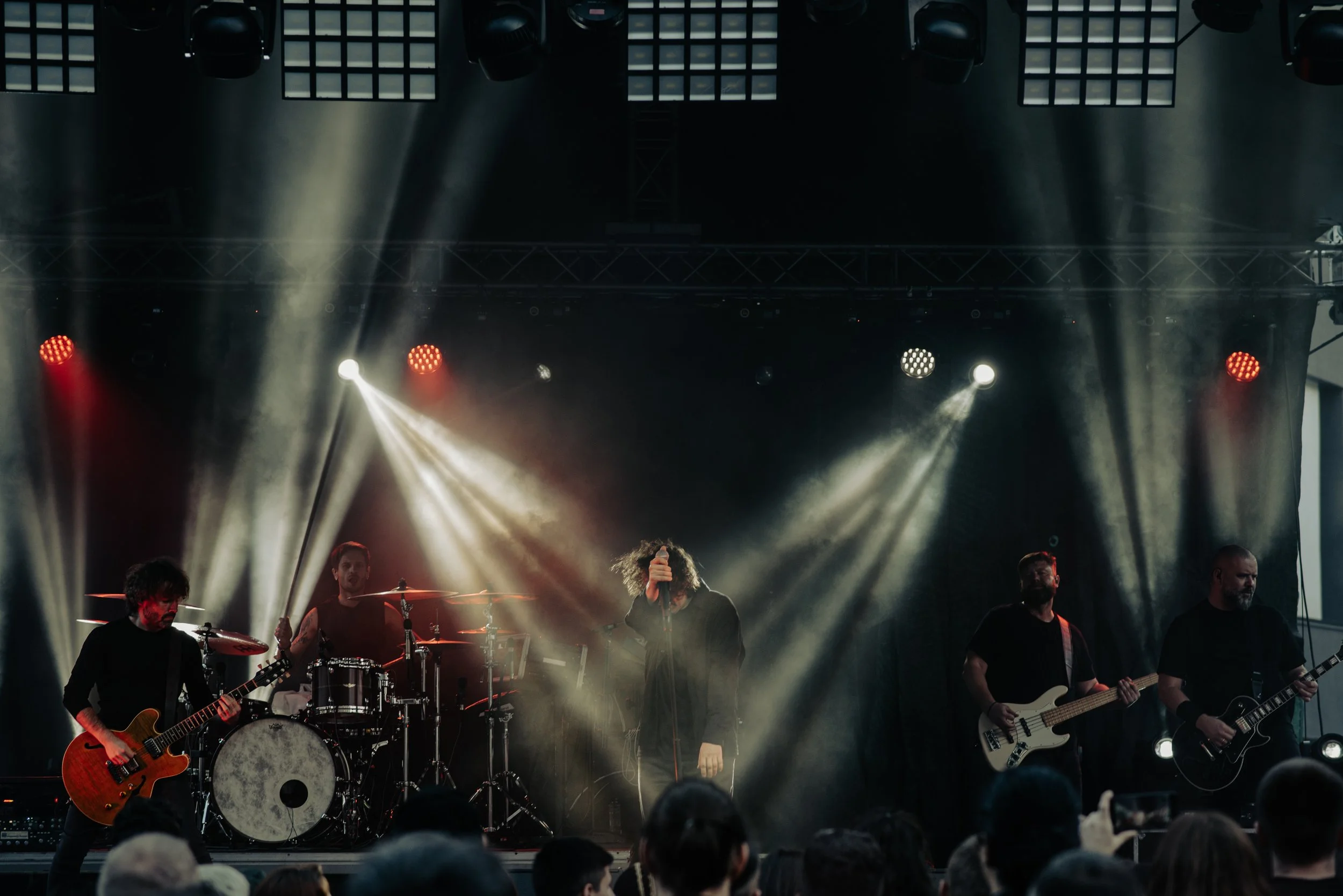 A band on stage performing at a concert with dramatic lighting.