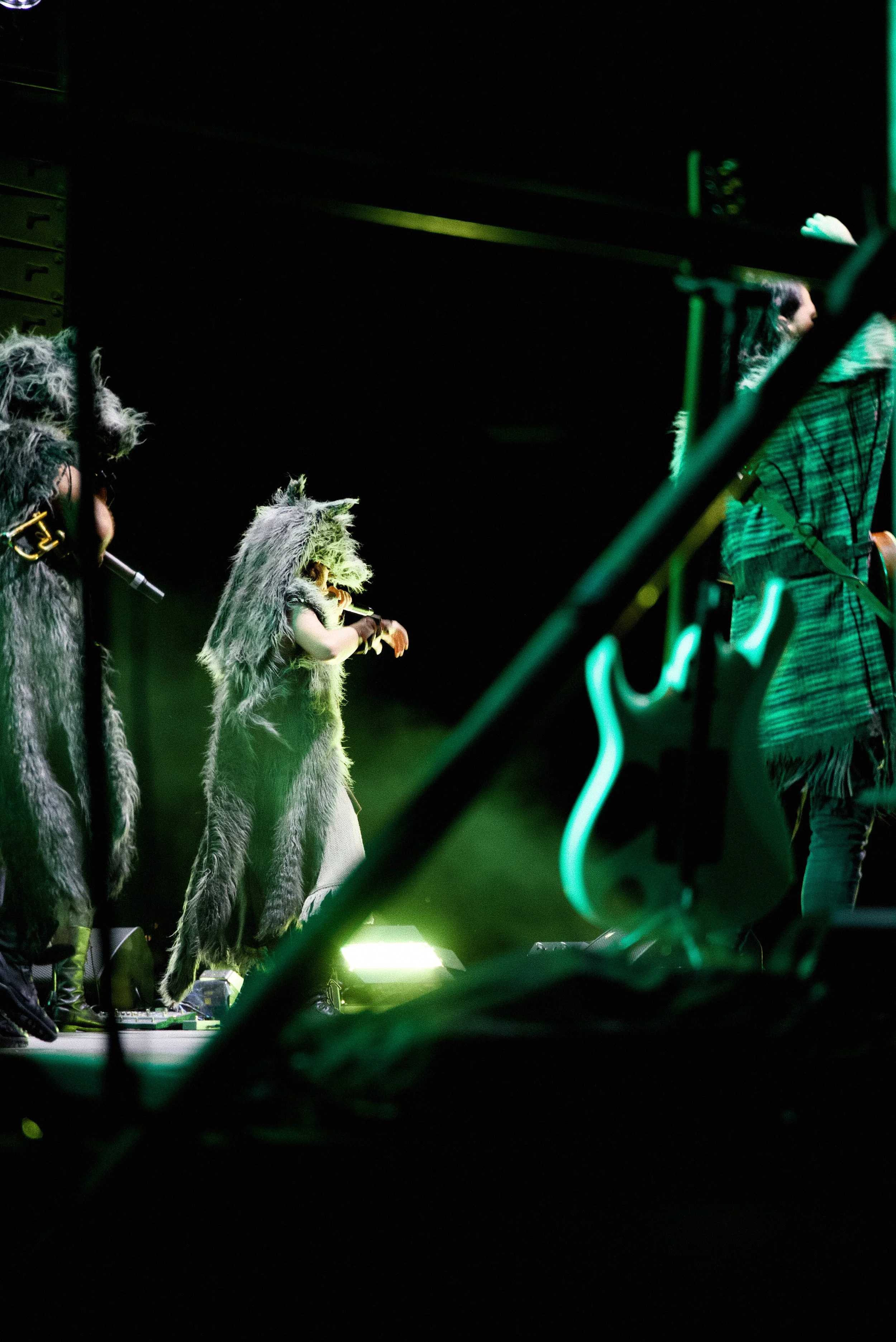 Musicians dressed in furry costumes performing on stage with stage lights.