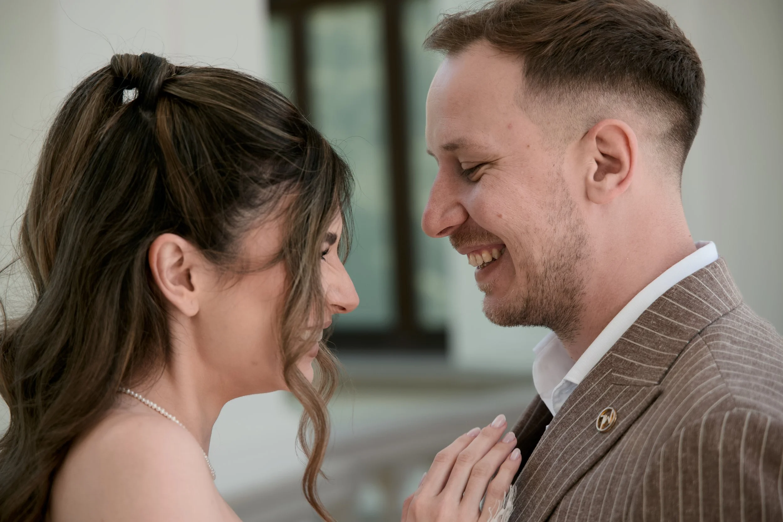 A smiling couple with their foreheads touching, dressed nicely, in a close-up portrait.