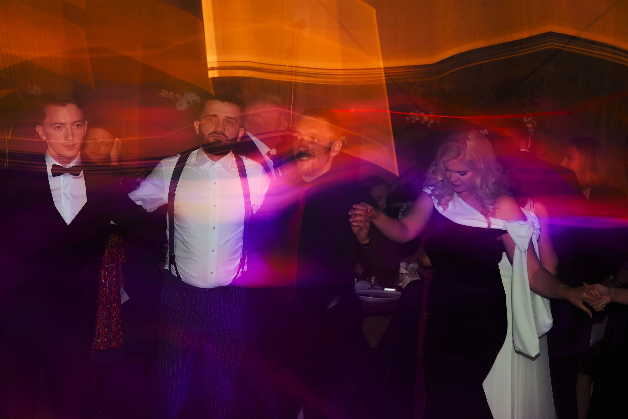 Group of people dancing at a party with colorful light streaks