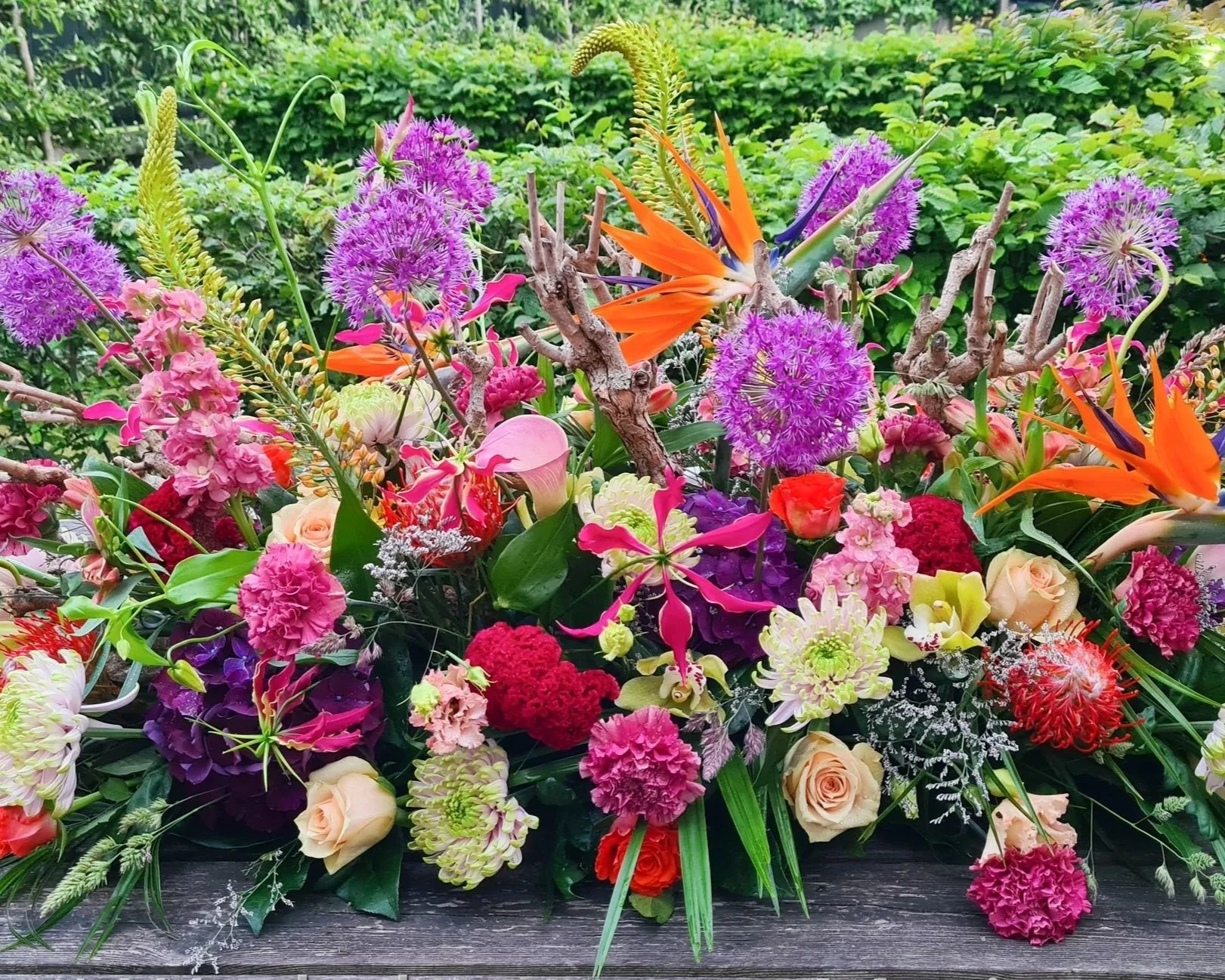 Kleurrijk rouwbloemstuk met roze bloemen en oranje strelitzia.jpg