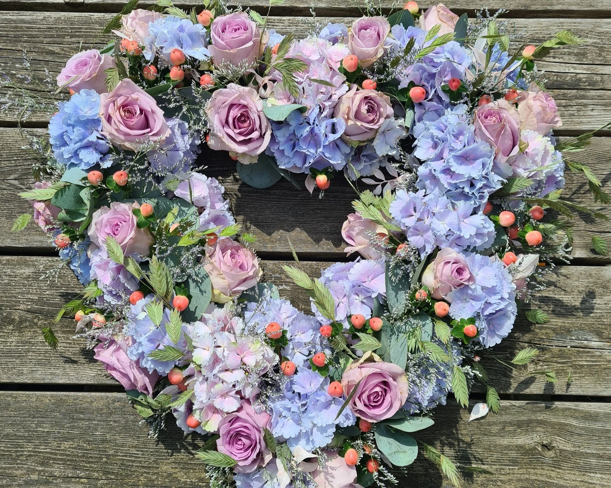 Hartvormig rouwbloemstuk met lila en roze bloemen.jpg