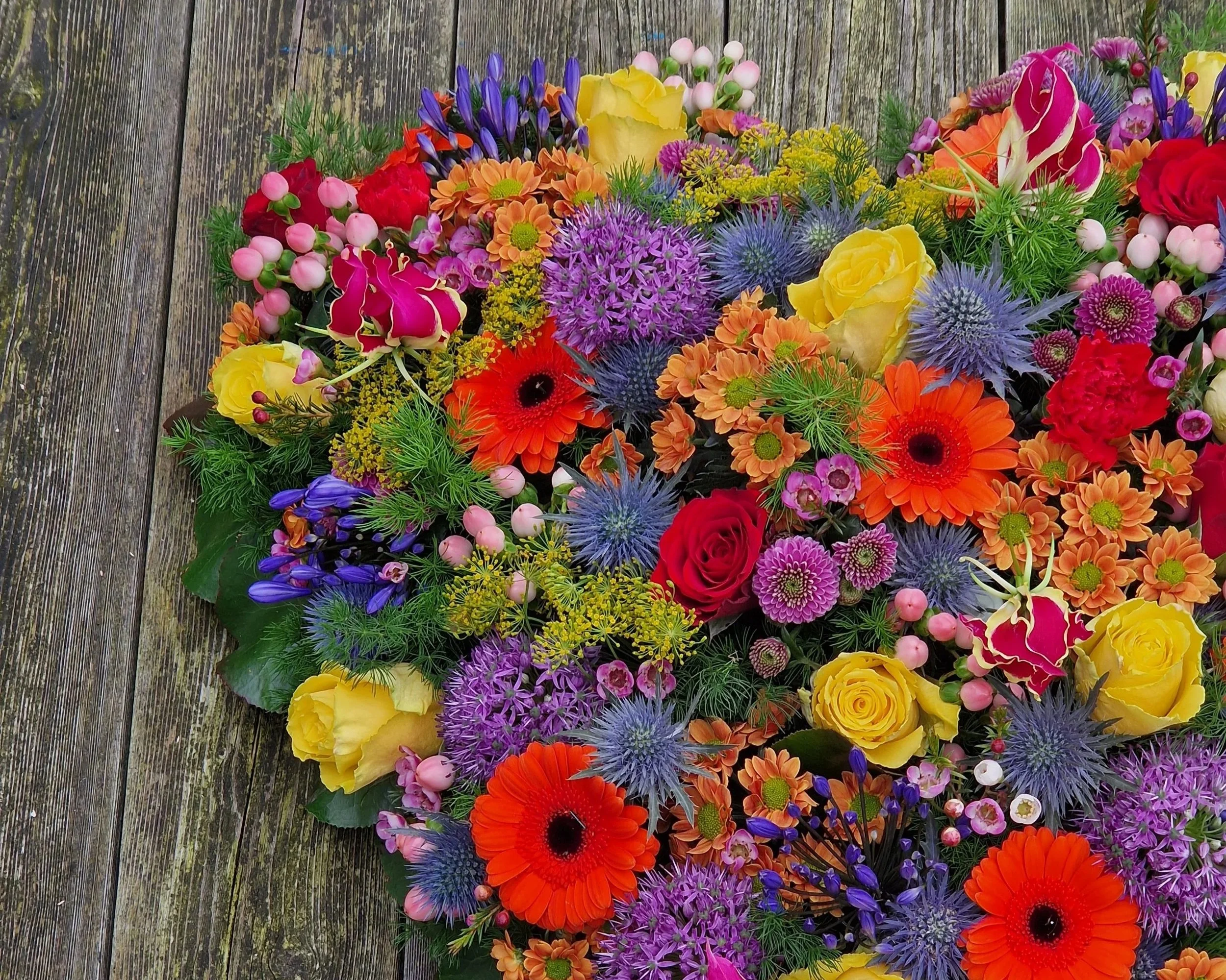 Kleurrijk rouwbloemstuk met oranje, paarse en roze bloemen.jpg
