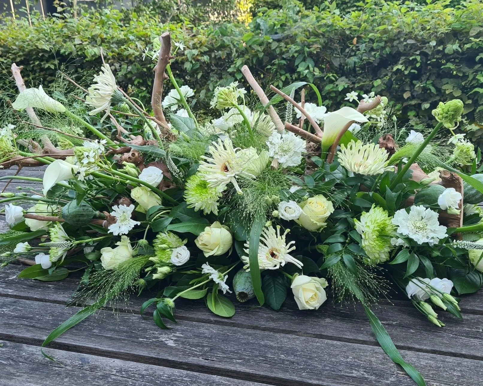 Wit rouwbloemstuk met takken en fris groen.jpg