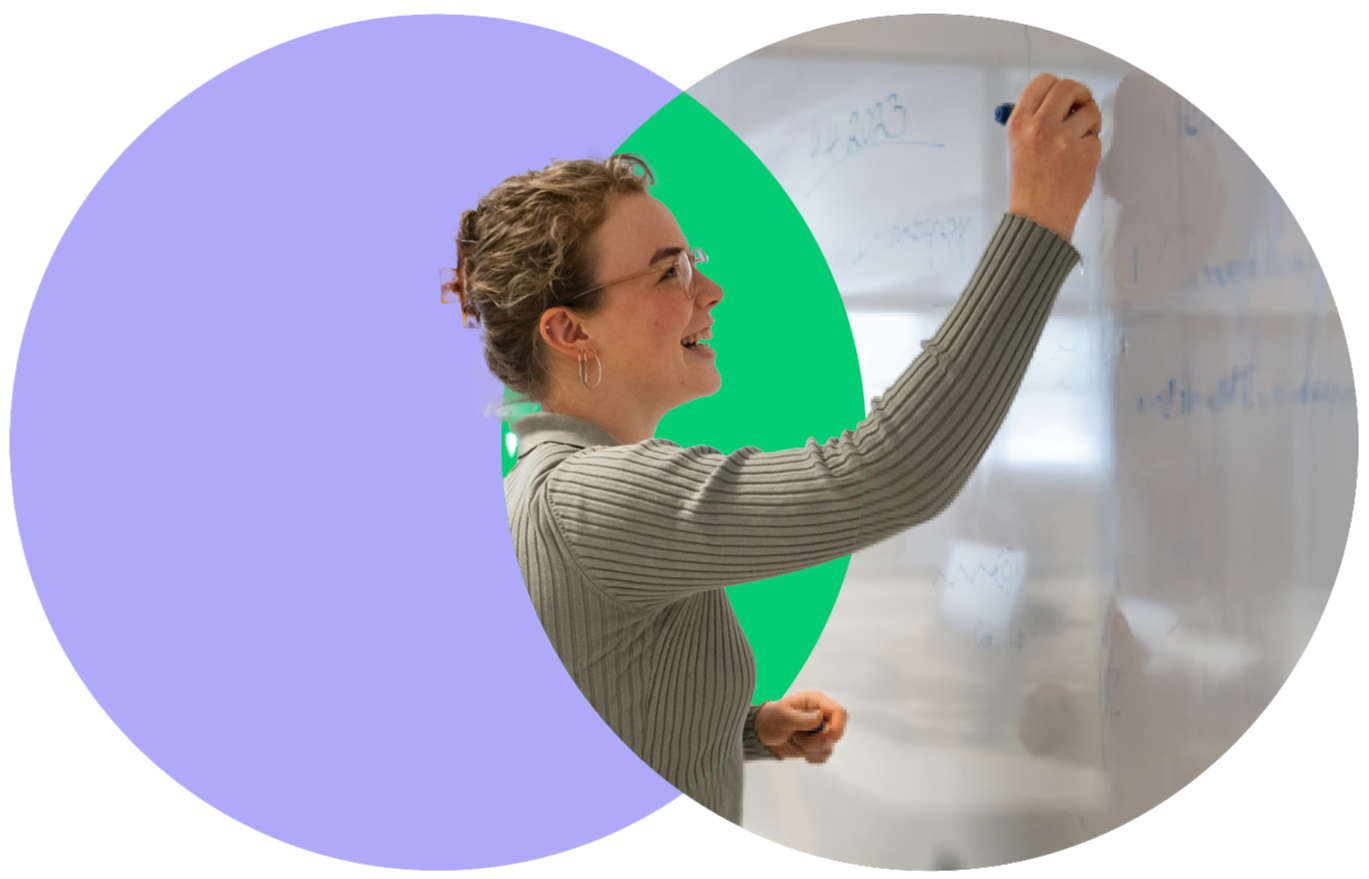 A young woman with glasses and earrings writing on a whiteboard in a classroom or office setting.