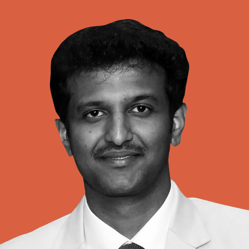 Black and white portrait of a smiling man wearing a suit against an orange background.
