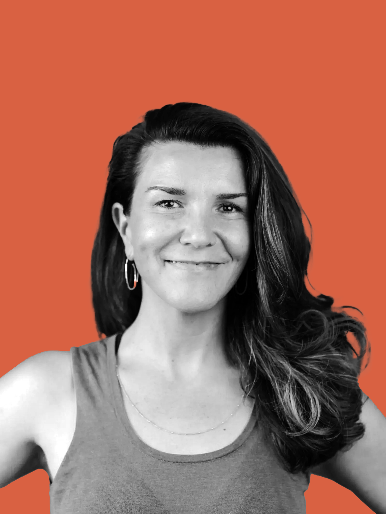 Portrait of a smiling woman with long wavy dark hair, wearing hoop earrings, a simple necklace, and a sleeveless top, with an orange background.