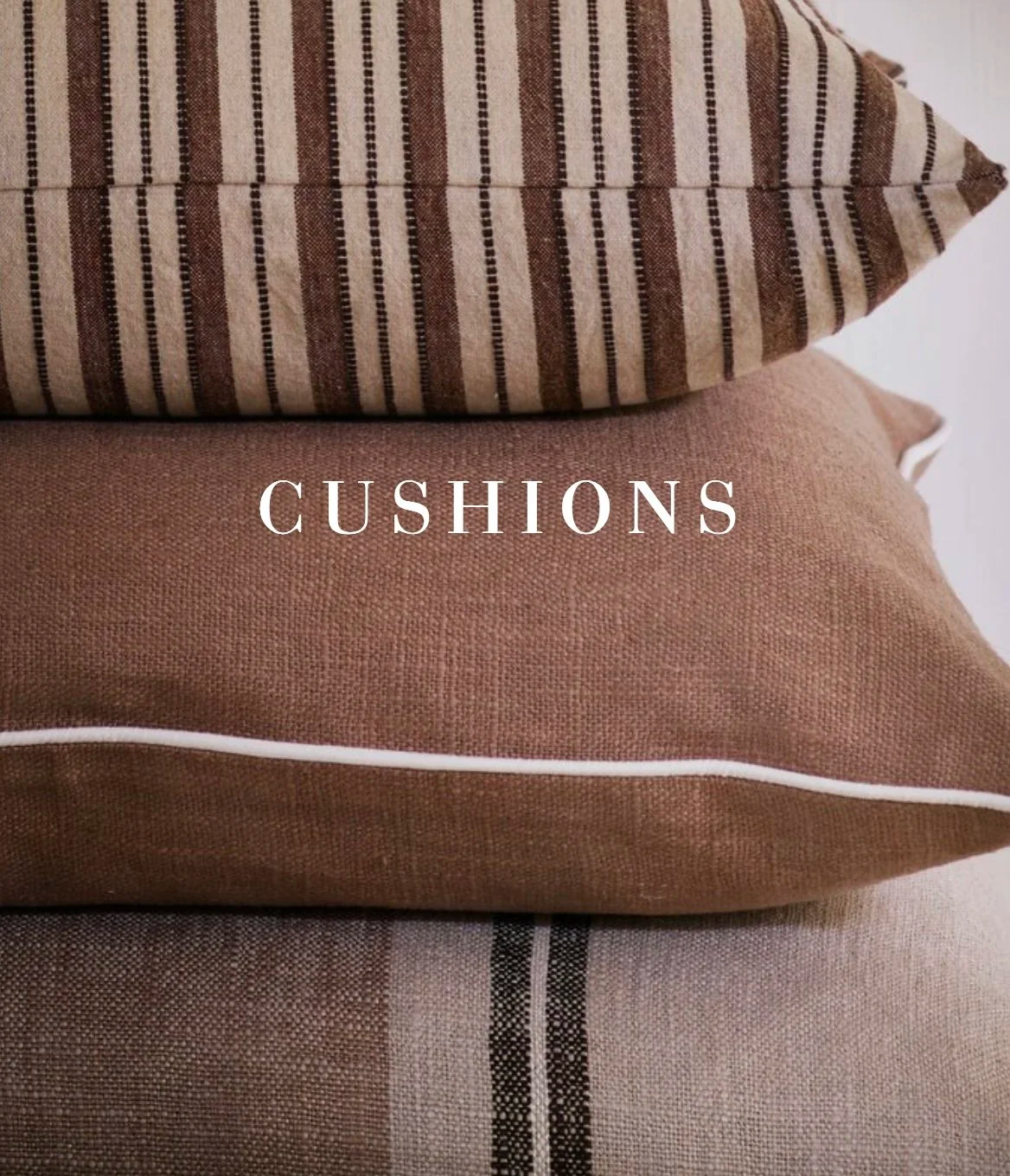 Close-up of three stacked pillows with different patterns and colors, with the word 'CUSHIONS' overlaid.