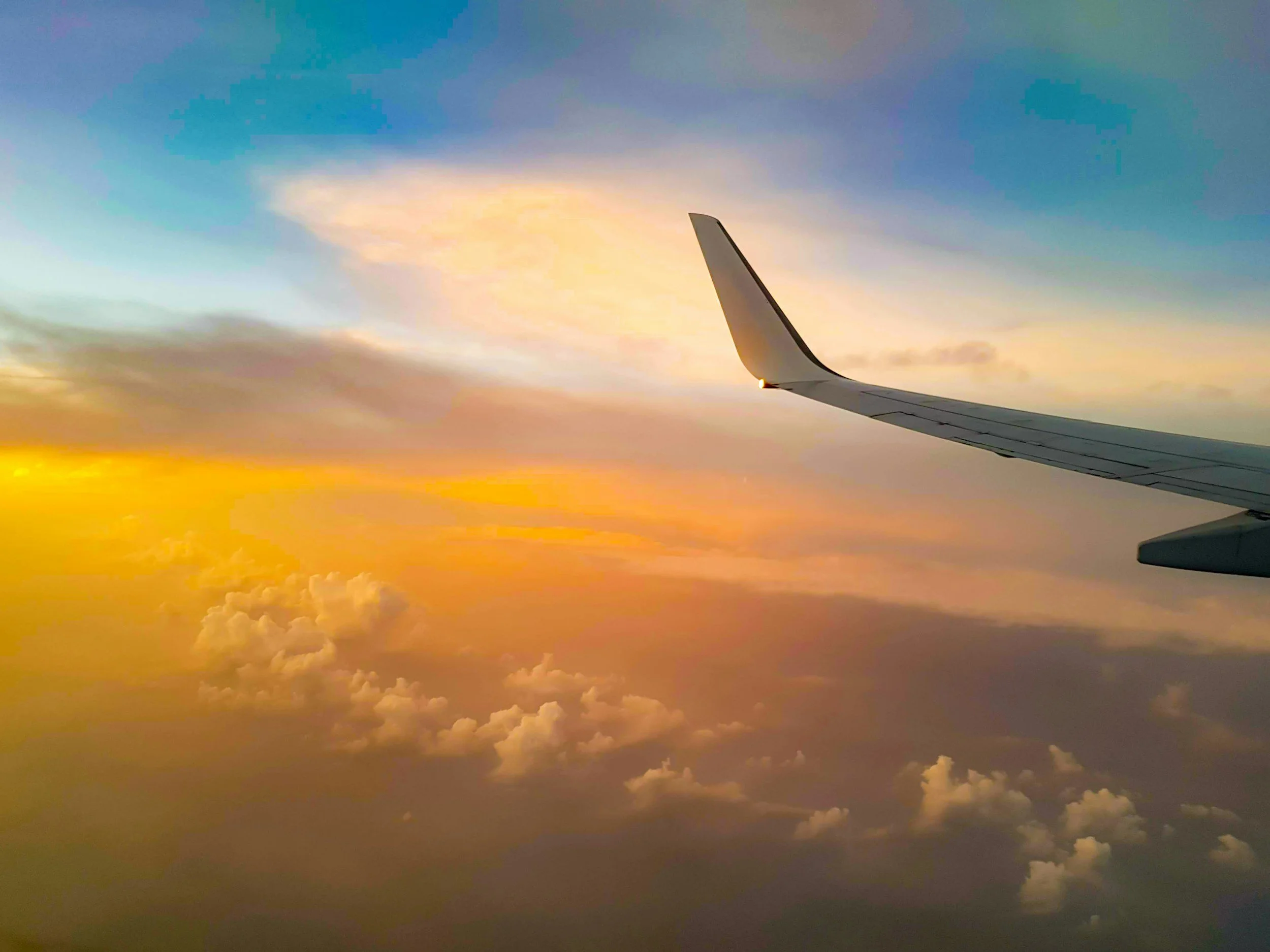 View of an airplane wing during sunset over clouds.