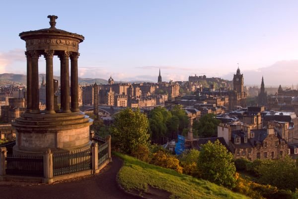 A historic monument with columns overlooking a city skyline with various buildings and green trees.