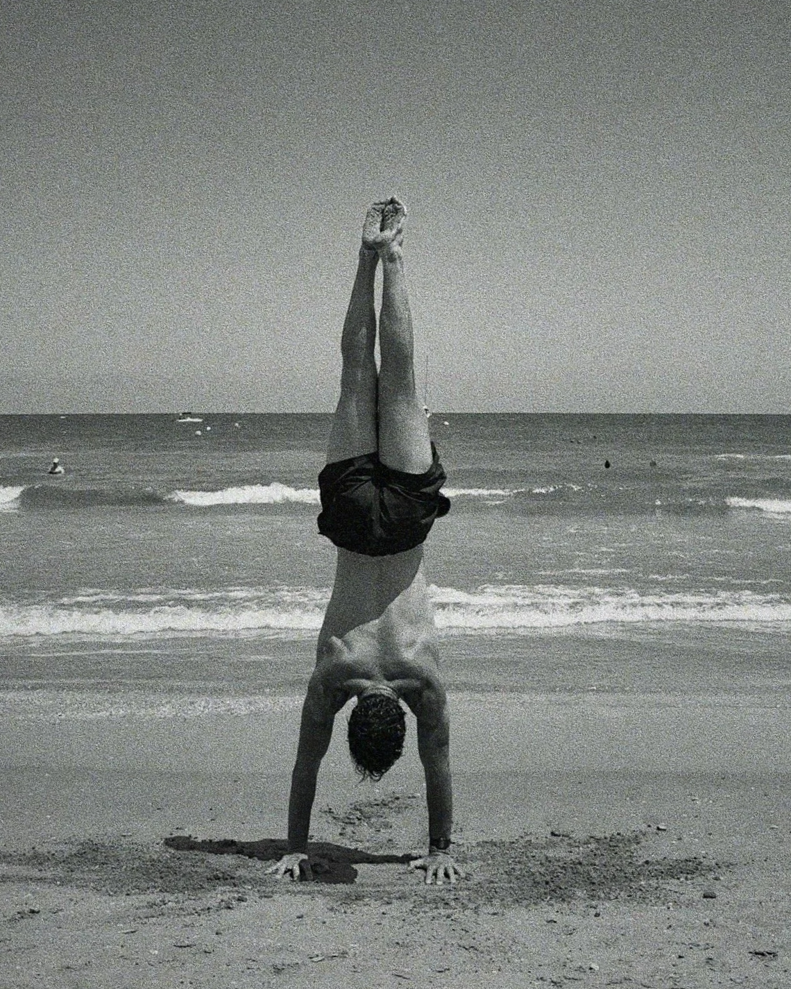 Victor performing a handstand by the sea in Spain  symbolising  roots  Kharax, a London based calisthenics brand focused on sculpting body and spirit