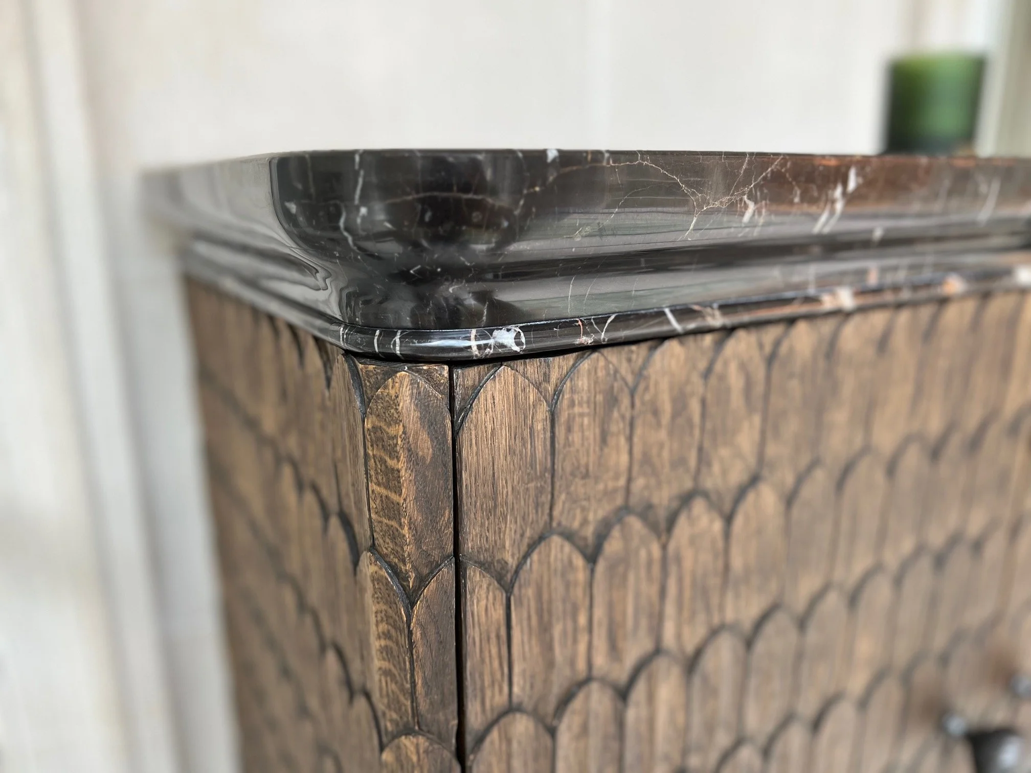 Close-up of a wooden cabinet with a black marble top and carving.