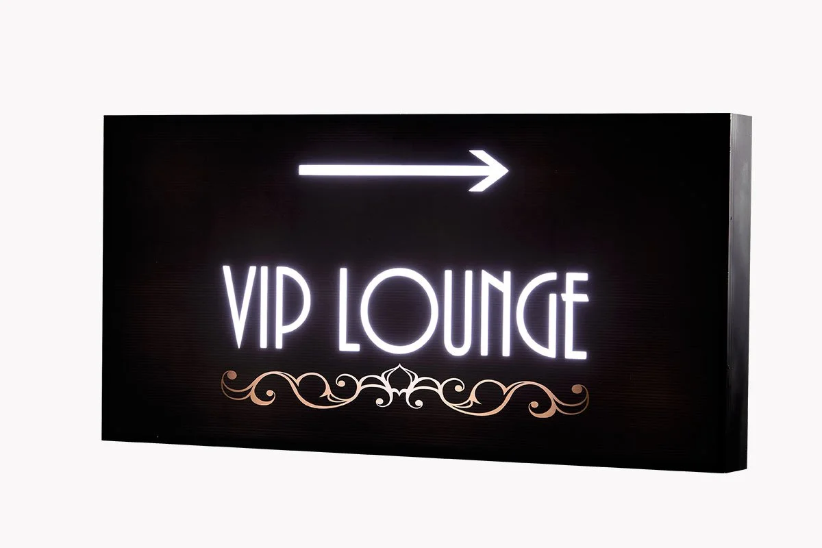 Black sign with white neon text reading 'VIP Lounge' and a white arrow pointing to the right.