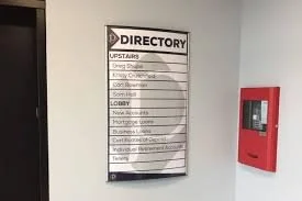 Hotel directory sign listing various floors and amenities, with a red fire alarm or emergency box mounted on the wall beside it.