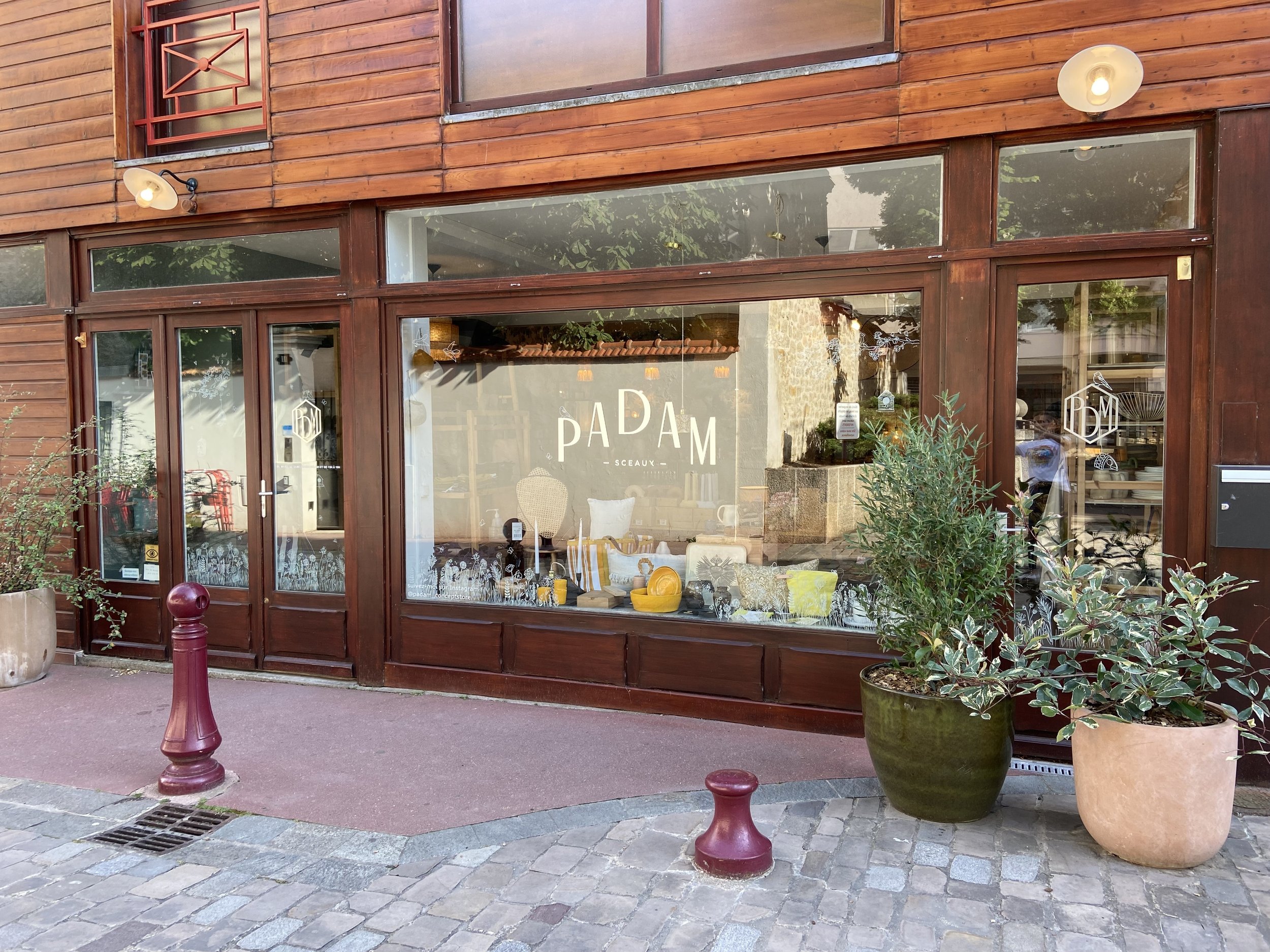 Vitrine d'un conceptstore en façade bois, plantes en pots et multiples objets colorés en vitrine