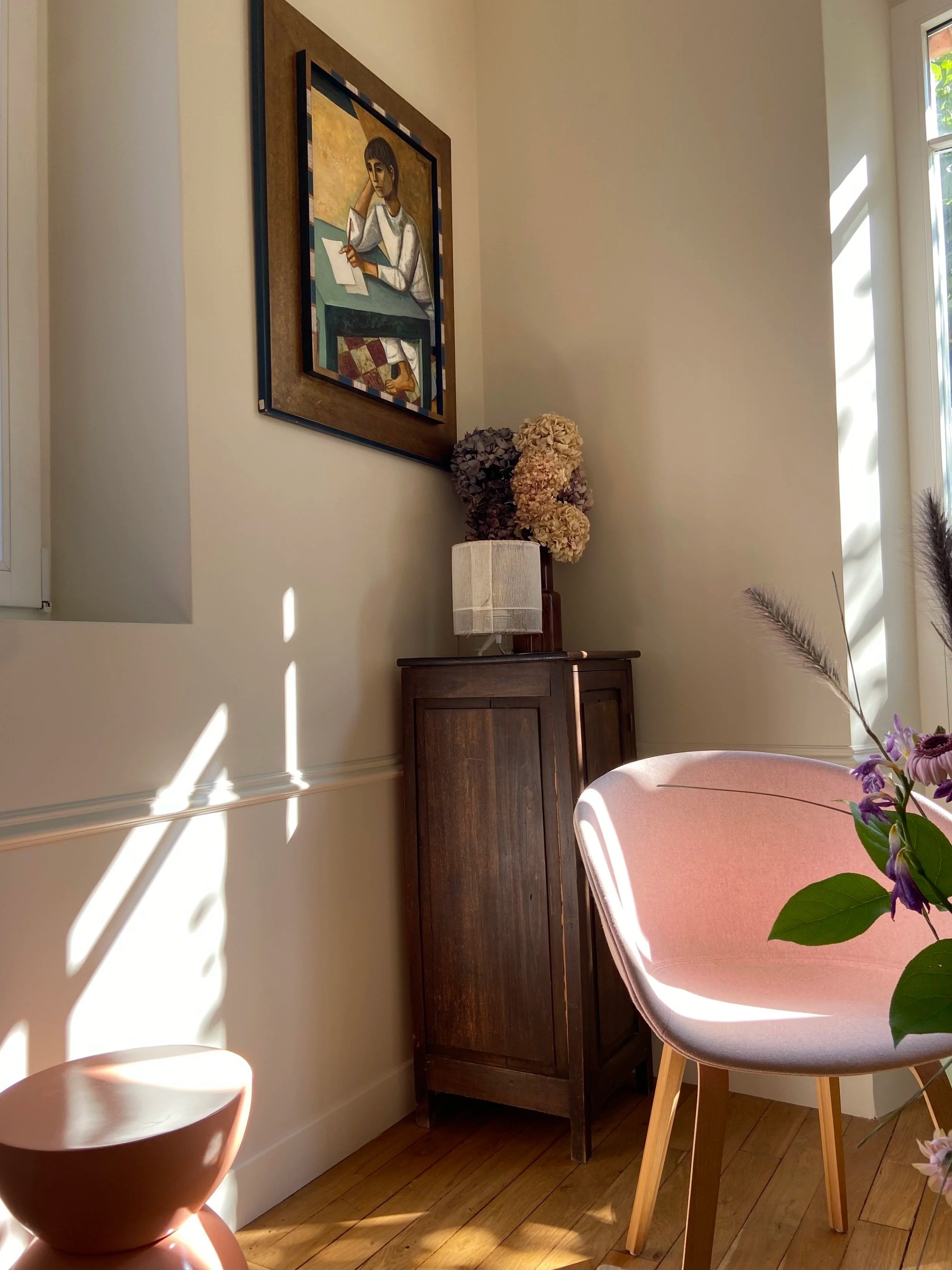 Salon avec moulures et parquet massif dans un meulière avec fauteuil rose et meuble chiné