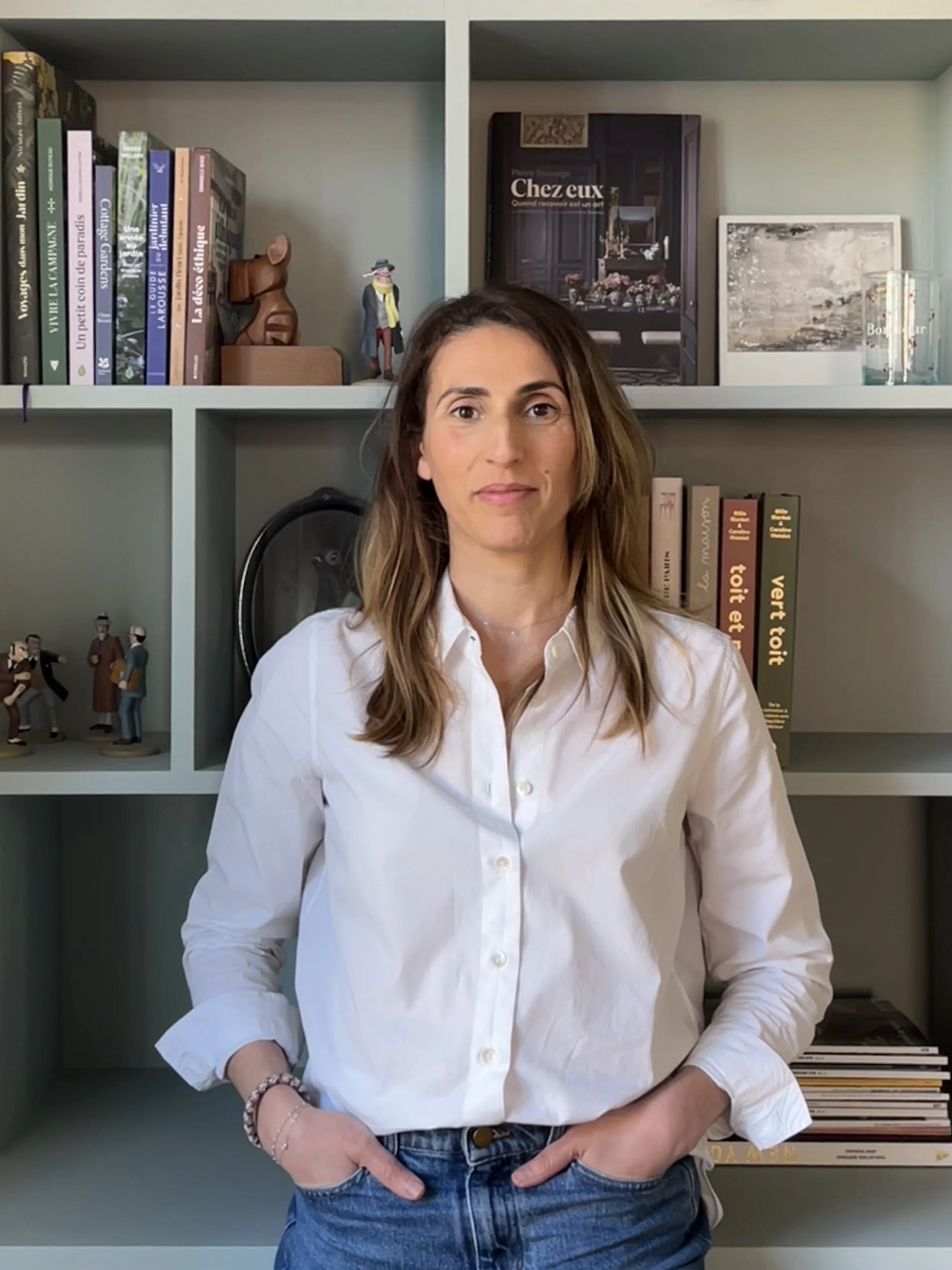 Portrait d'une femme brune souriante et bienveillante devant une bibliothèque