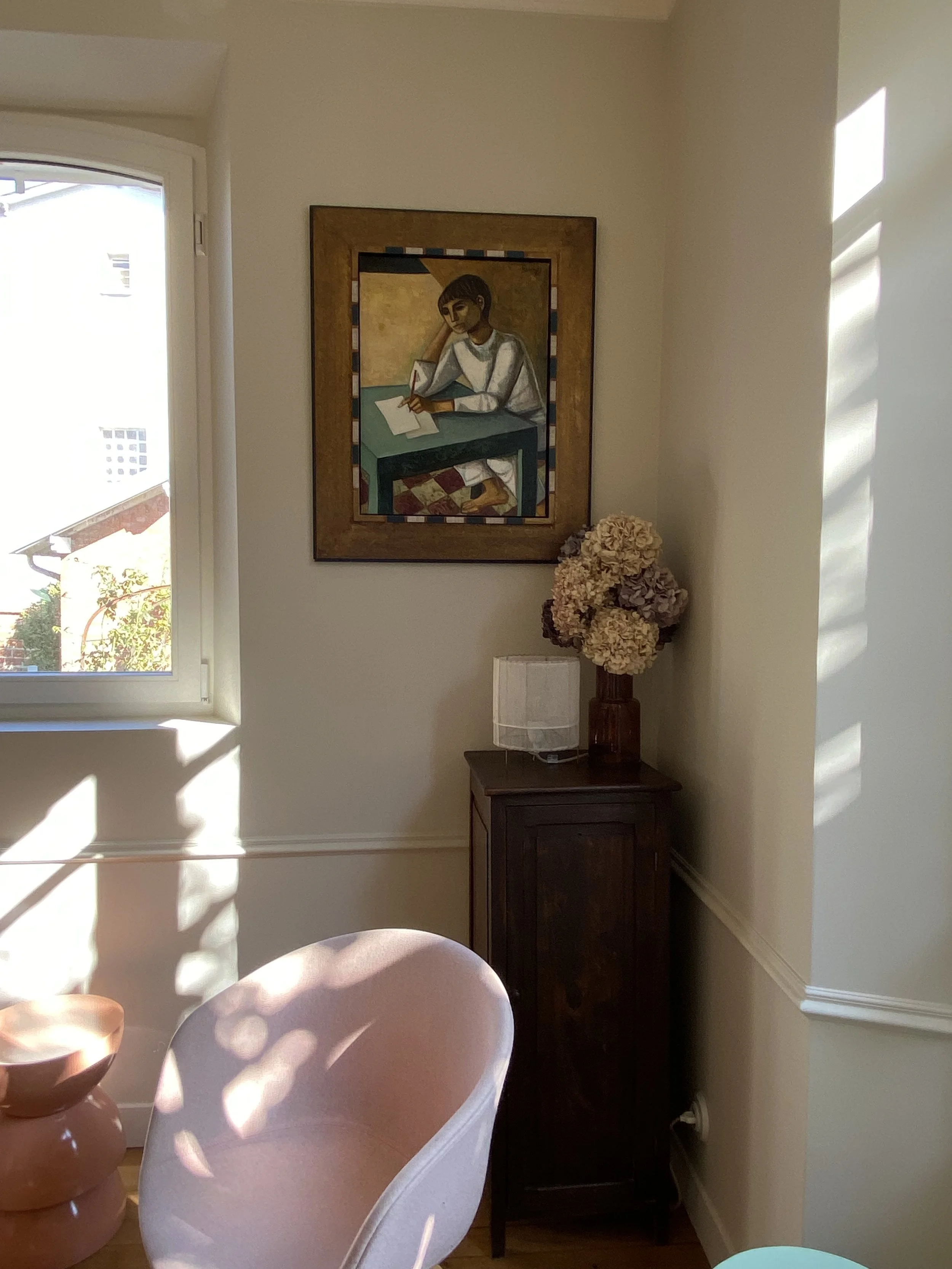 Détail d'un salon dans une meulière 1900 avec moulures, parquet ancien, meubles chinés, fauteuil rose, fleurs séchées et tabouret rose