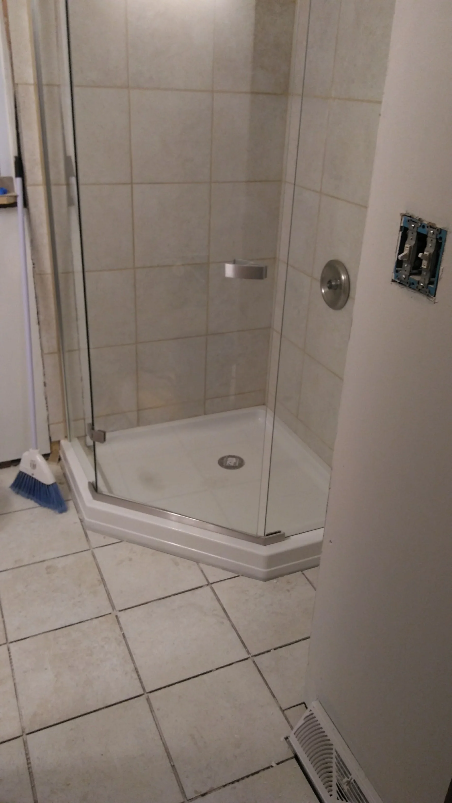 Glass shower enclosure with tiled interior and a drain on the shower floor.