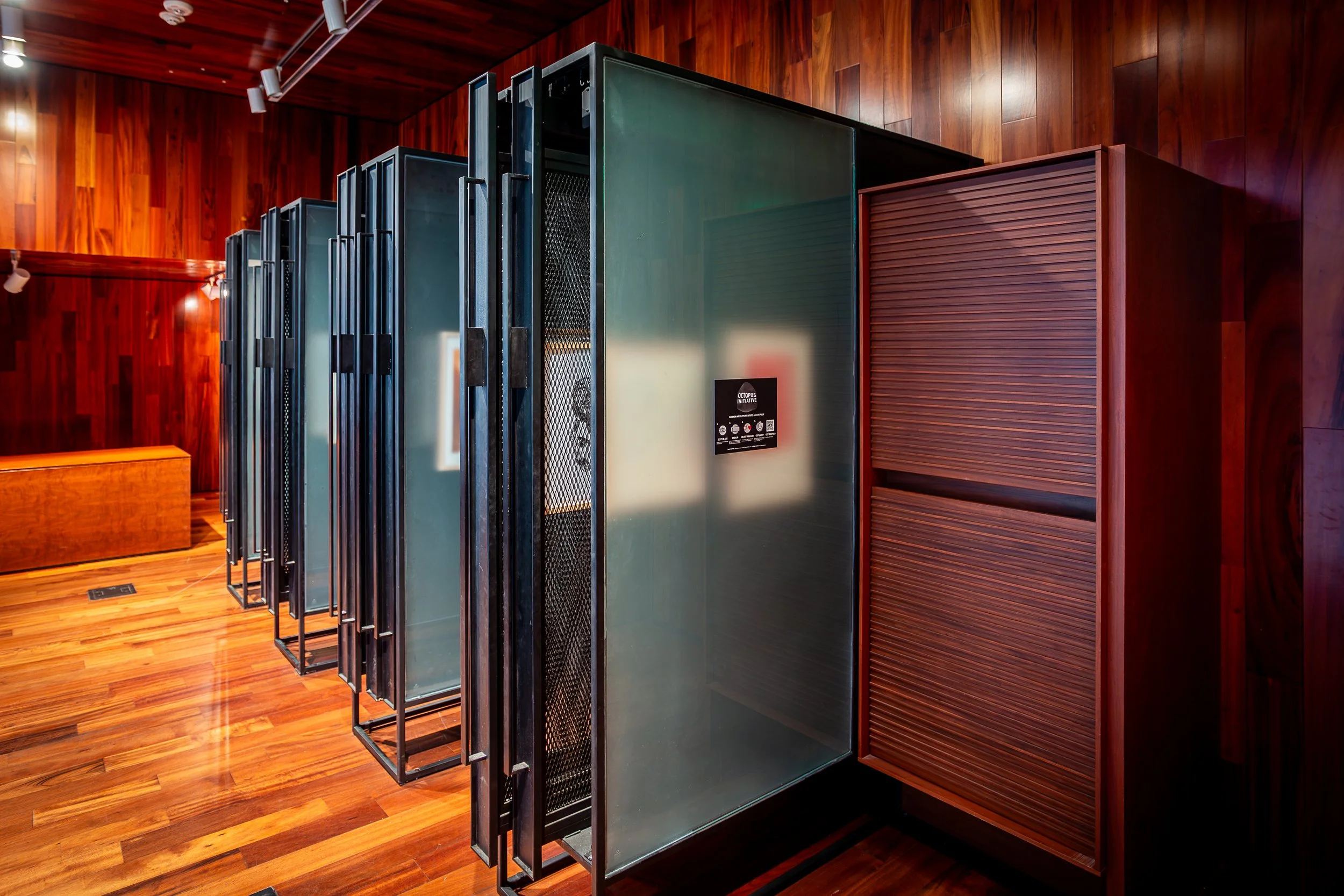 Row of vintage arcade game machines in a room with wood-paneled walls and floor.