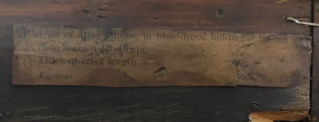 Close-up of a weathered wooden plaque with faint, partially visible black text, possibly displaying measurements or instructions.