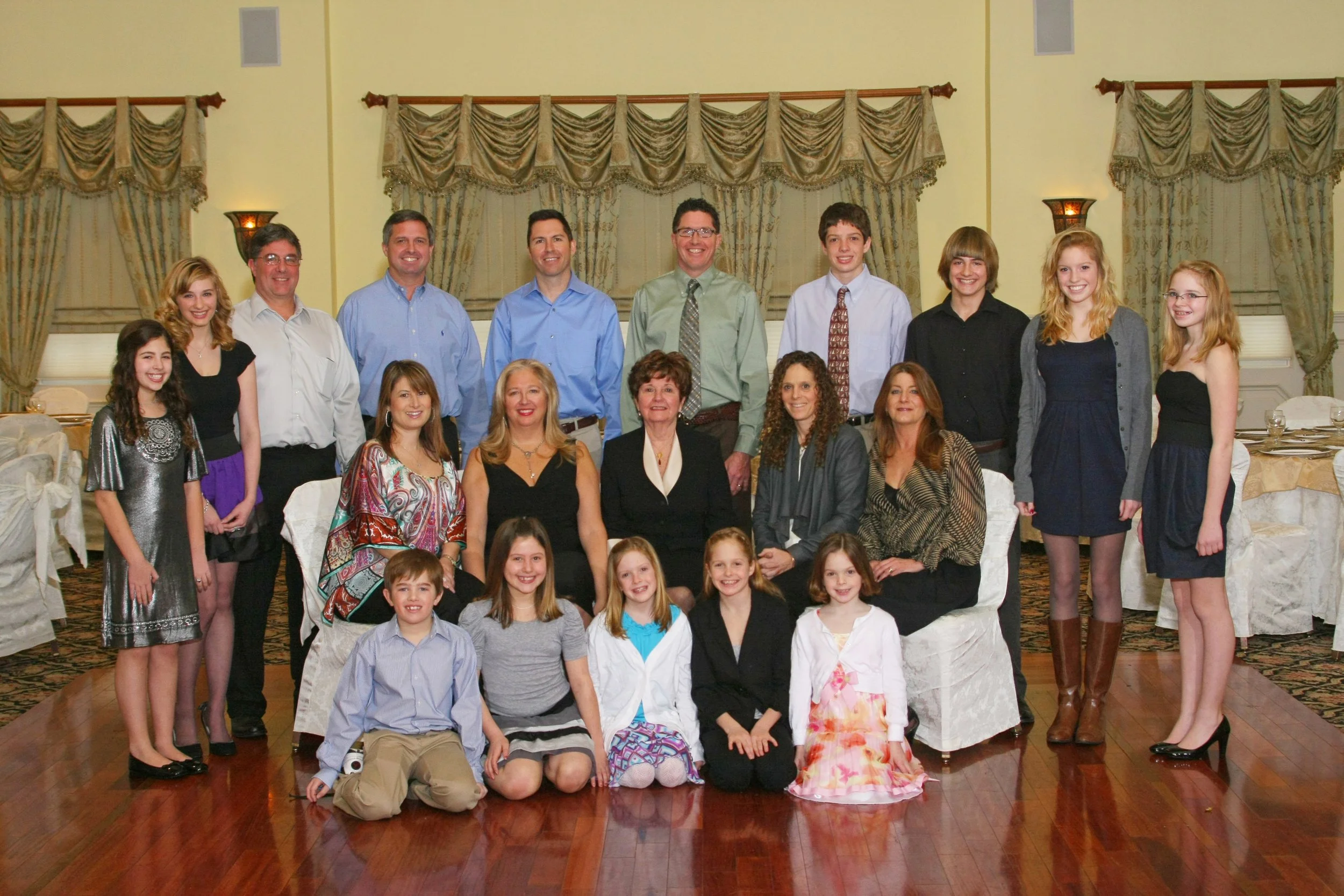 Group of people gathered for a photo indoors, standing and sitting in front of decorated curtains and tables set for an event at the Brickhouse of Wyckoff, NJ..