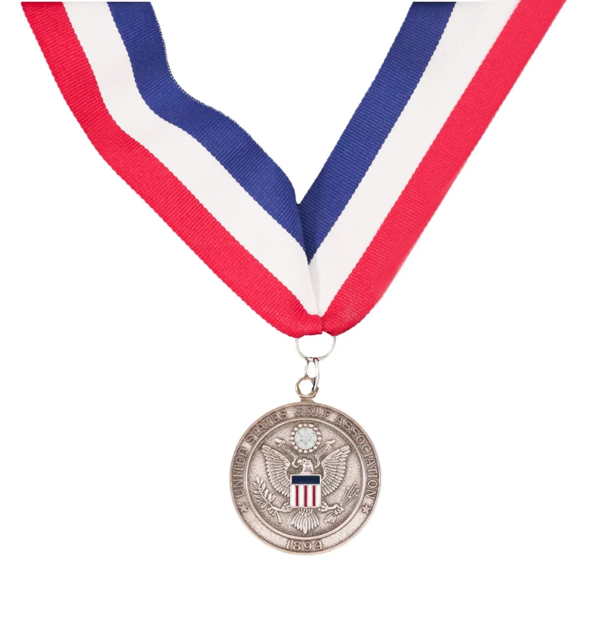 A silver medal hanging from a red, white, and blue ribbon, featuring an eagle emblem and the inscription 'United States Golf Association 1894'.