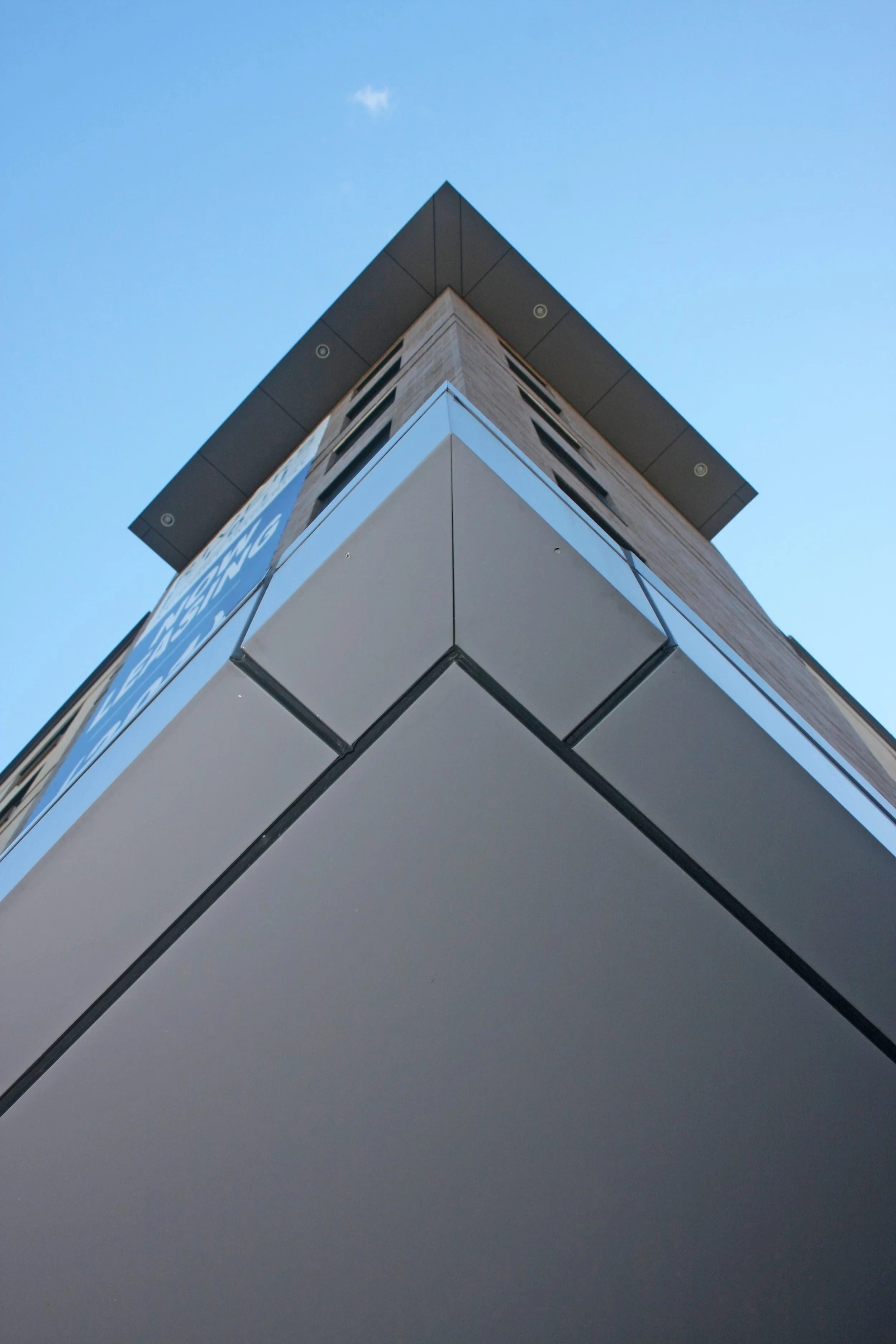 Low-angle view of a modern building with glass and metal exterior against a clear blue sky.