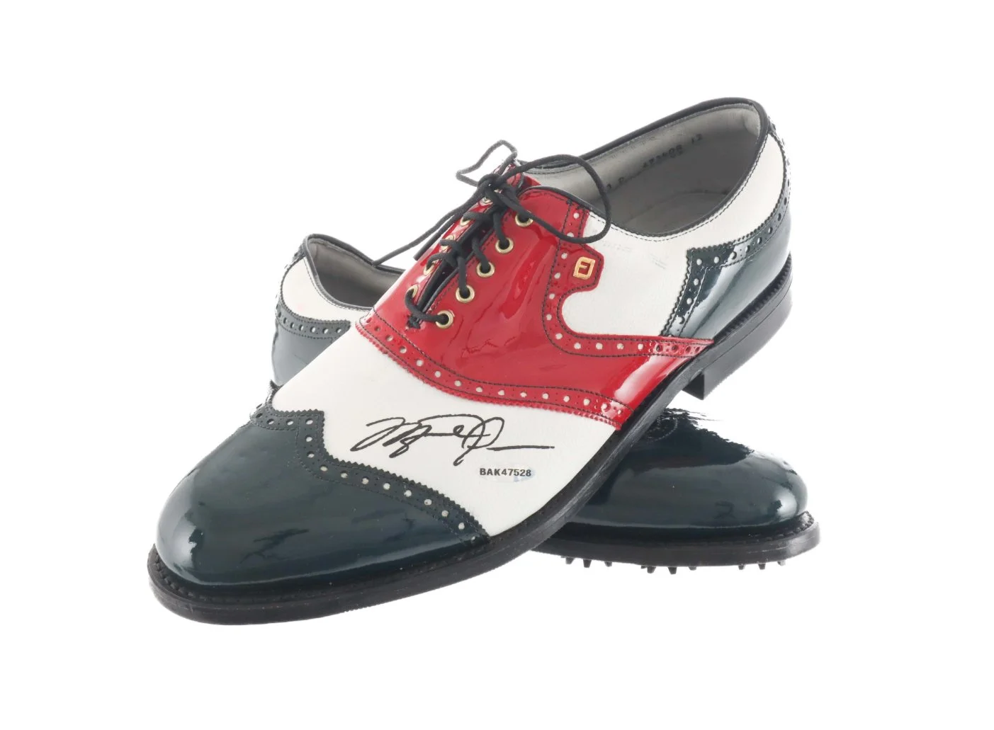 A pair of novelty golf shoes designed to look like classic men's dress shoes, with red, white, and black coloring, featuring a signature and a barcode, placed against a plain background.