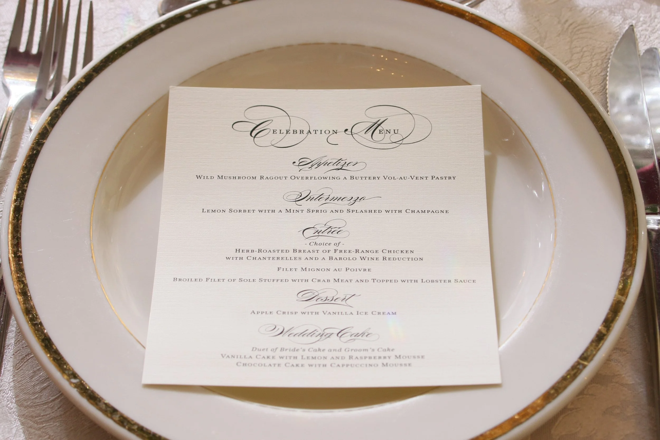 Wedding menu placed in a decorative plate. The menu has elegant cursive and serif font, listing appetizer, entree, dessert, and wedding cake options.