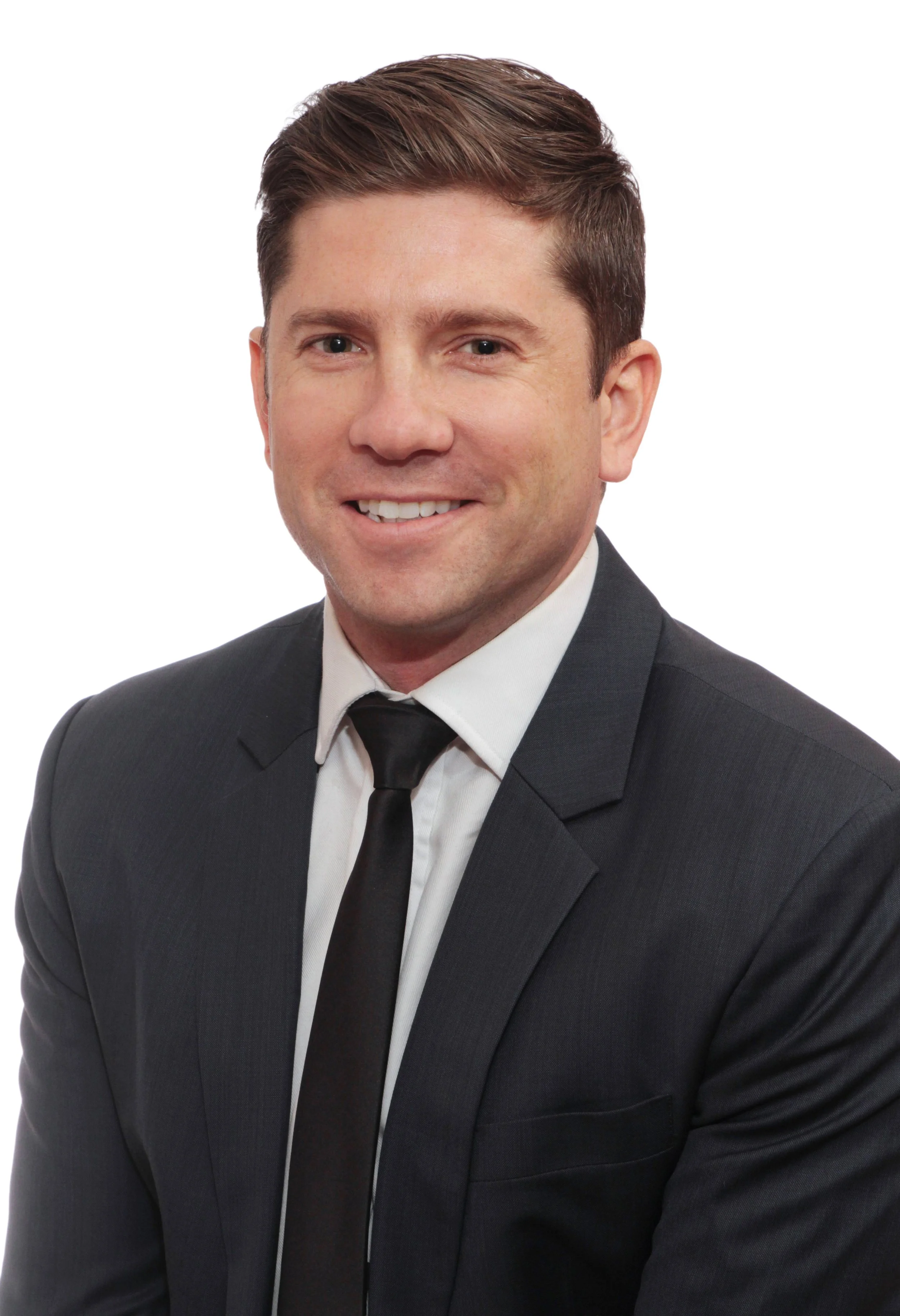 A man with light skin, brown hair, dressed in a dark suit, white shirt, and black tie, smiling at the camera for LLinkedIn.