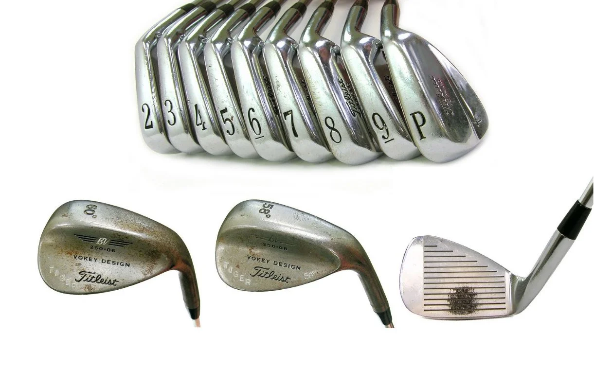 Set of golf clubs including numbered irons and wedges, arranged vertically and horizontally on a white background.