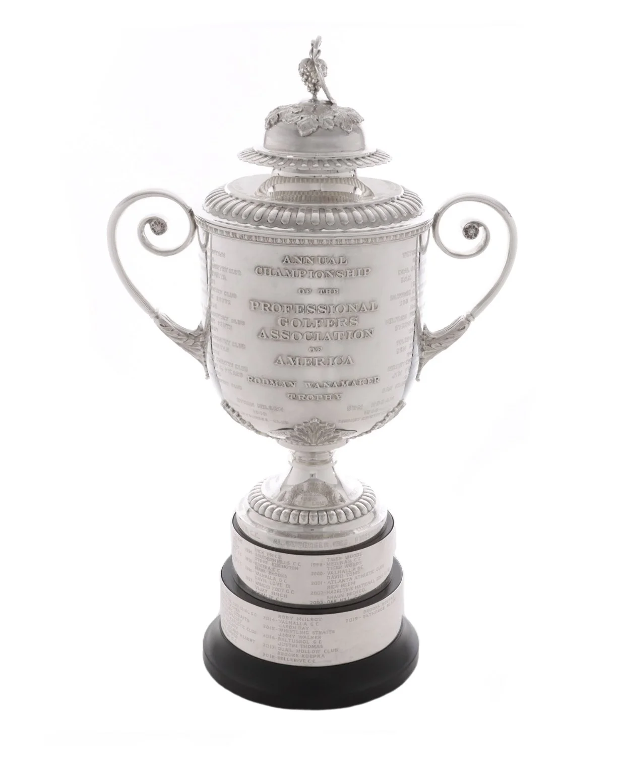 Silver trophy cup with inscriptions listing winners of the annual professional golfers association of America rodman wanamaker trophy, set against a plain white background.