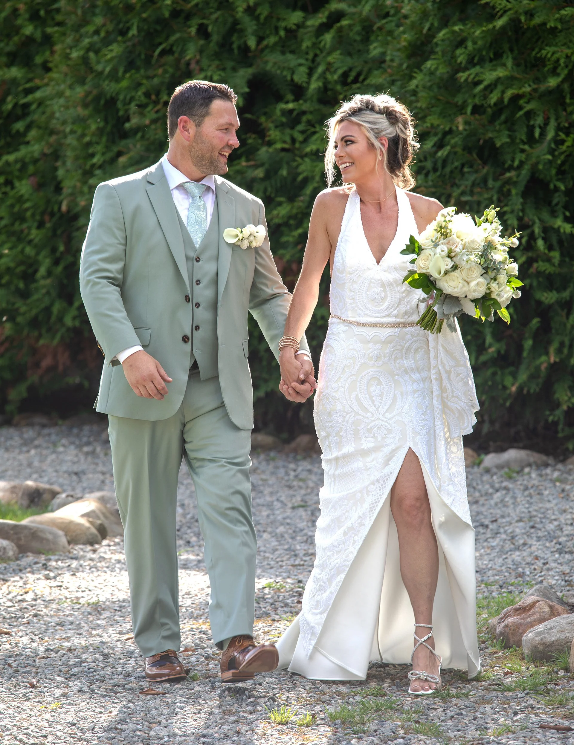 Bride with bouquet in a wedding dress and Groom in a green suit walking in the gardens at the Ramsey Golf and Country Club in Ramsey NJ