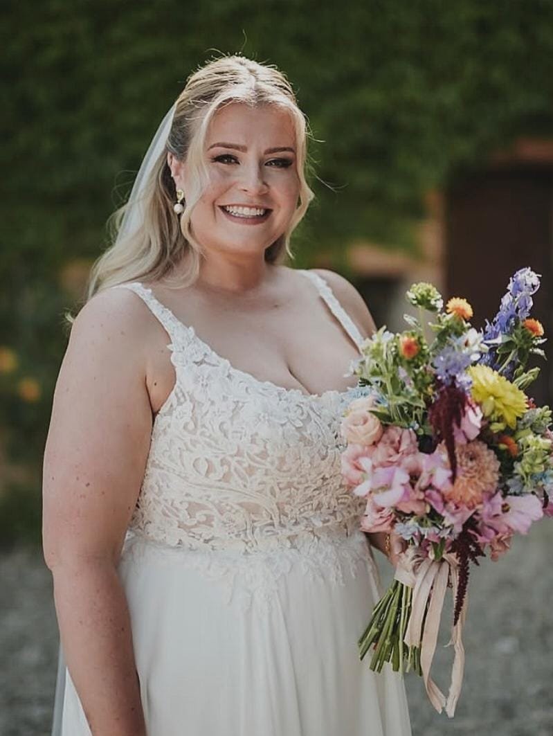 A bride in her ivory lace bodice dress with her colourful bouquet in italy