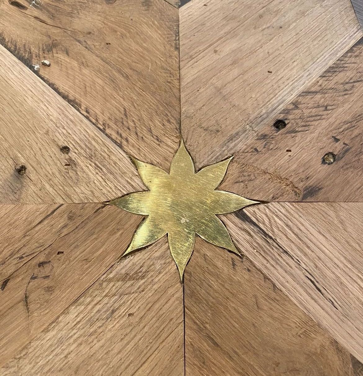 Close-up of a wooden floor with a decorative metal star-shaped piece at the center.