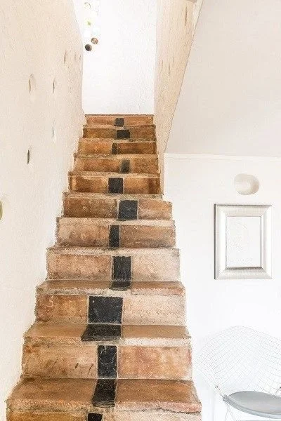 Indoor staircase with brown steps and a black line with black squares running down the center.
