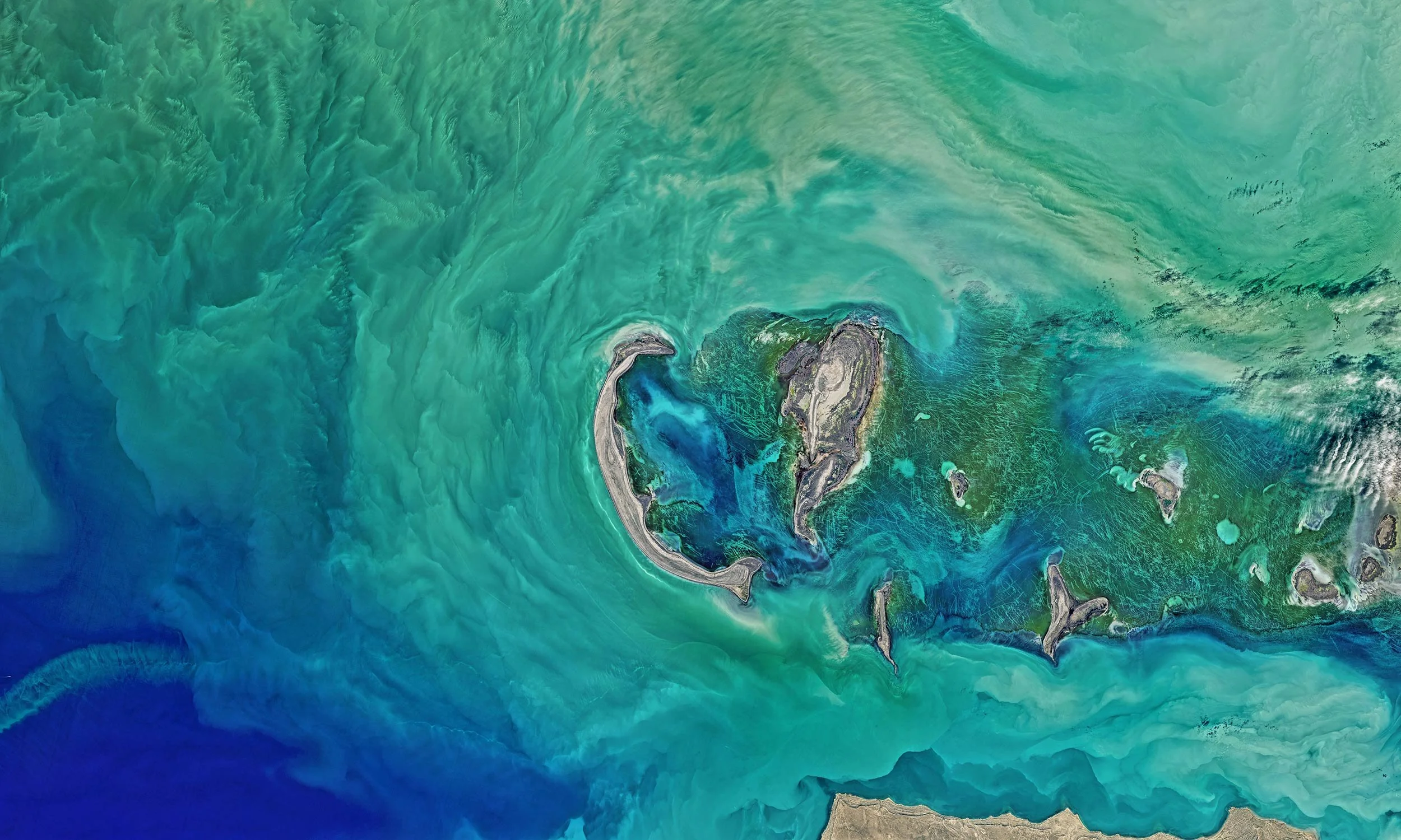 Satellite image of a tropical island with surrounding coral reefs and turquoise blue waters.