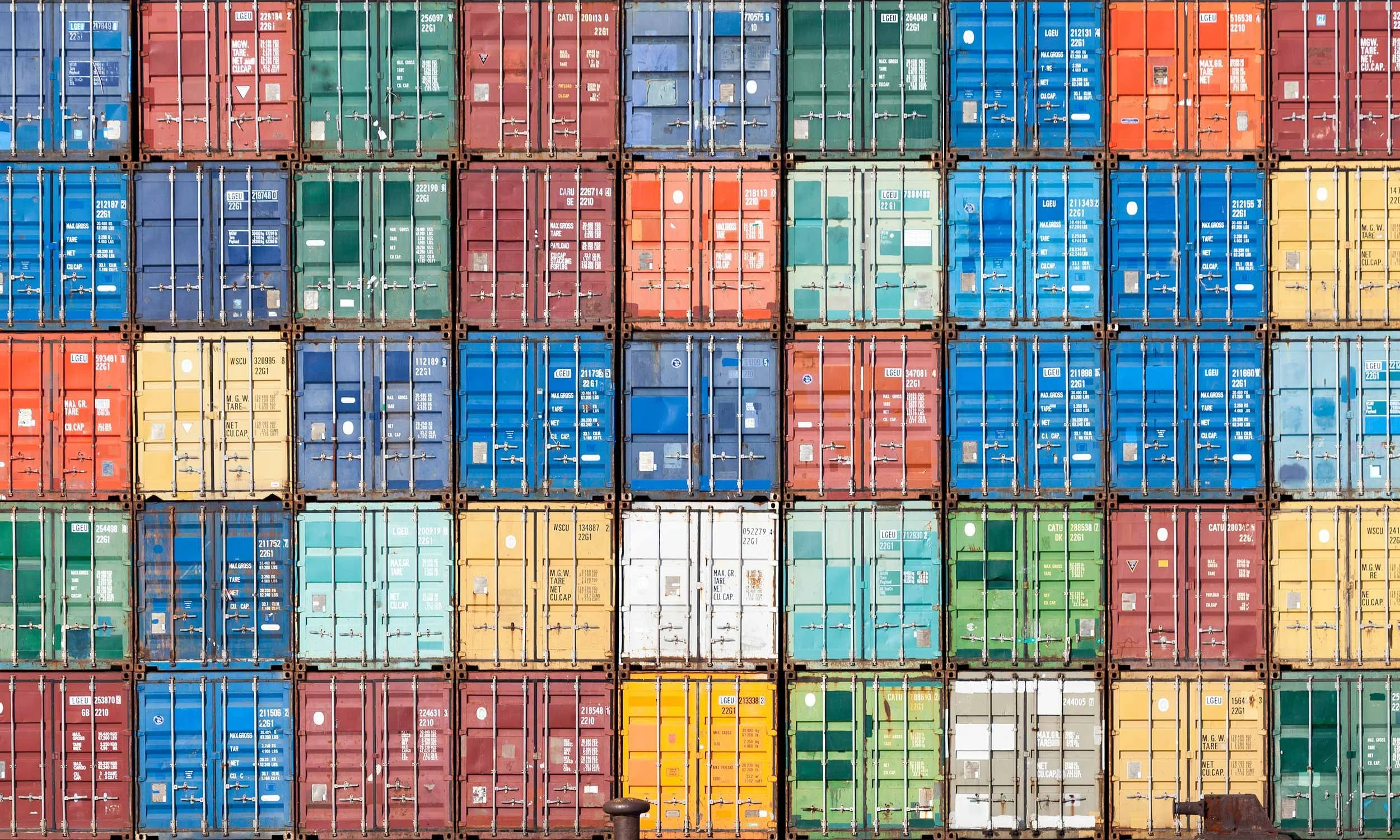 Colorful stack of shipping containers arranged in a grid pattern at a port.