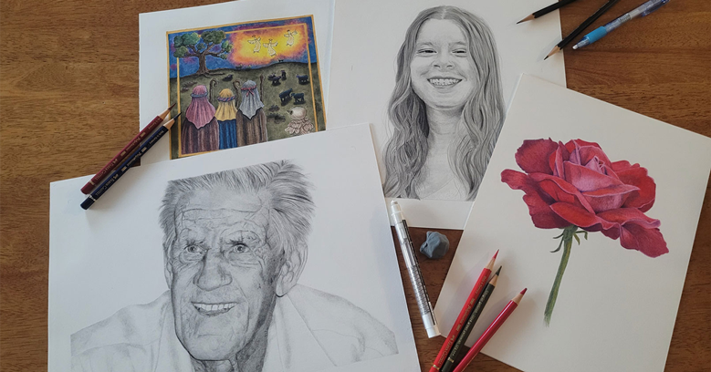 Sketches of a smiling elderly man, a young woman, and a red rose, along with a color print of a landscape painting on a wooden table with various drawing tools.