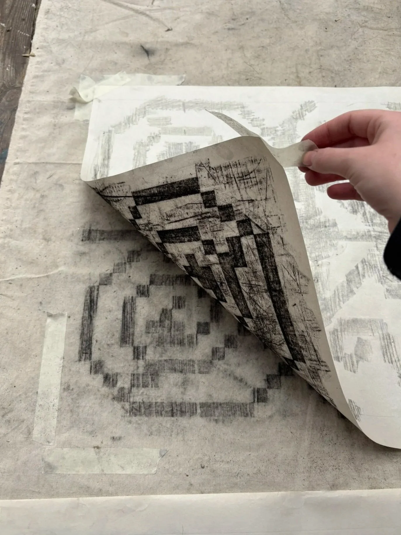 Person peeling paper with black ink printing from a surface.