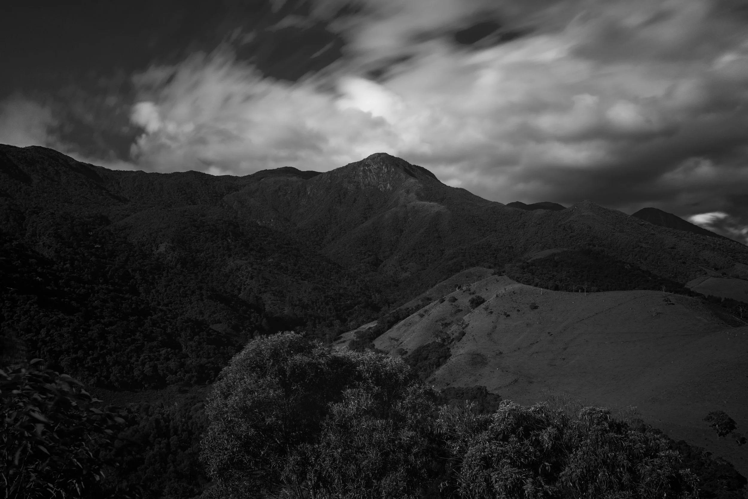 Black and white photo of a mountain range with a cloudy sky.