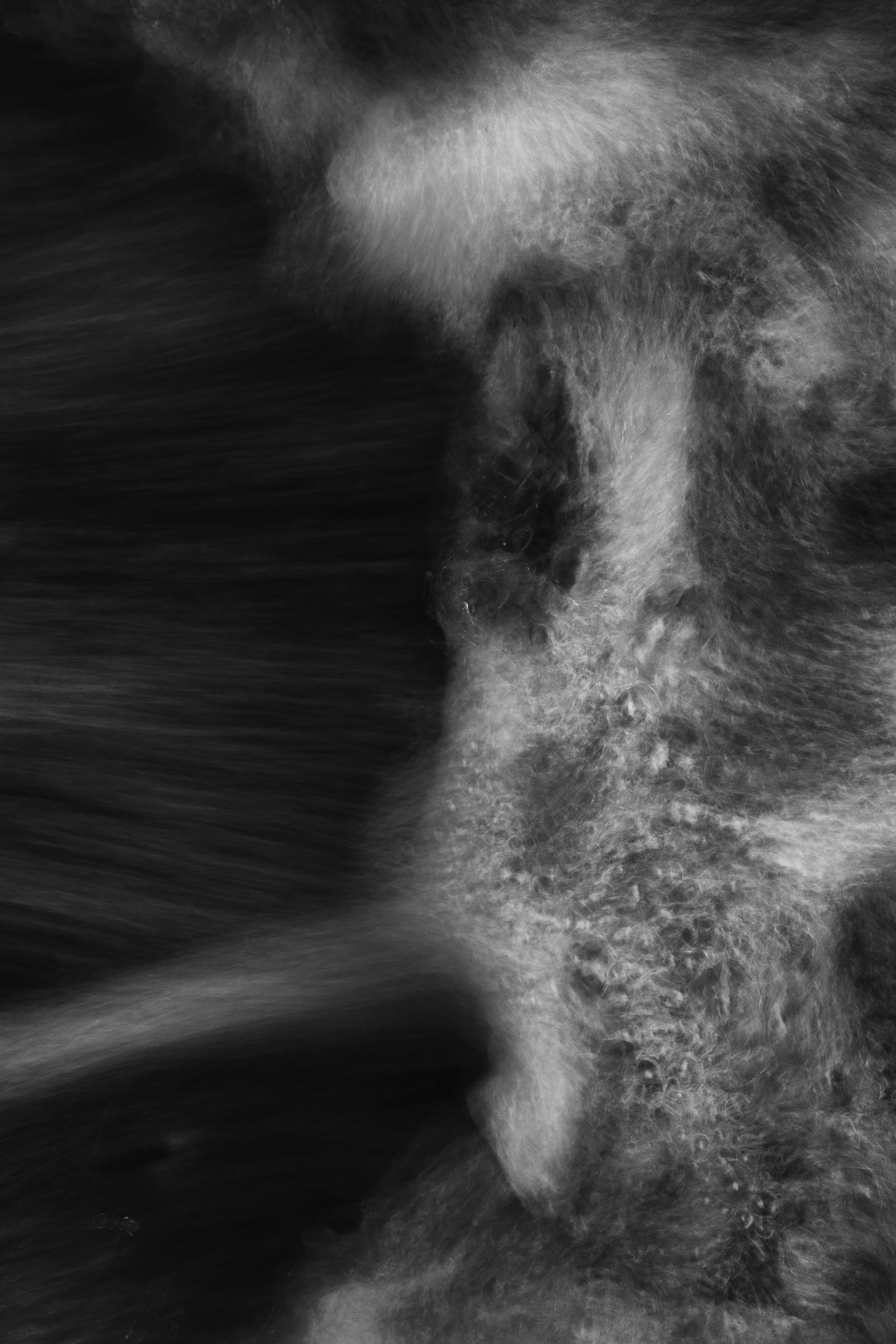 Black and white photograph capturing the movement of water, emphasizing the texture and flow of the waves.