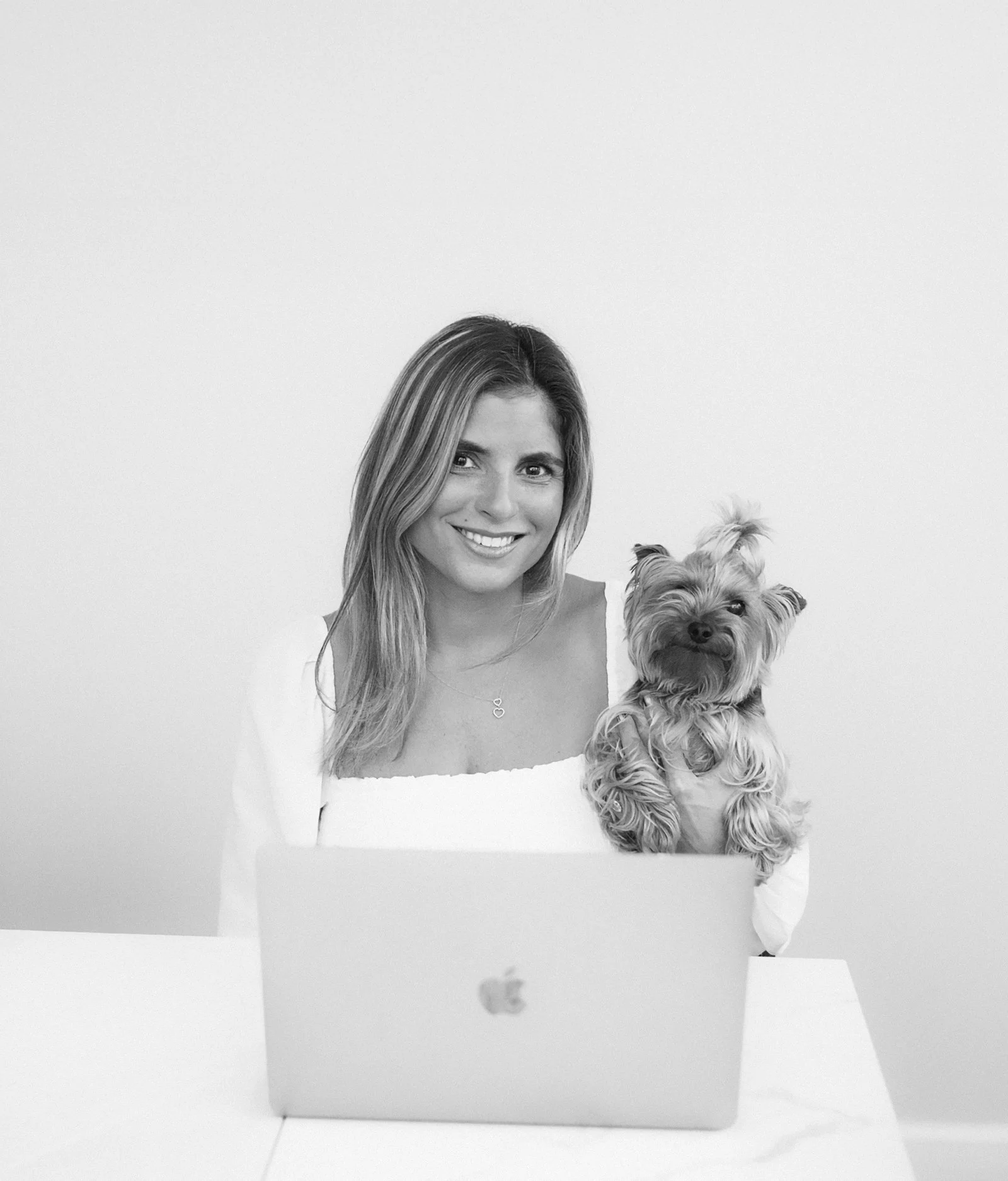 A woman with long hair holding a small dog on a white table, recreated as a collage.