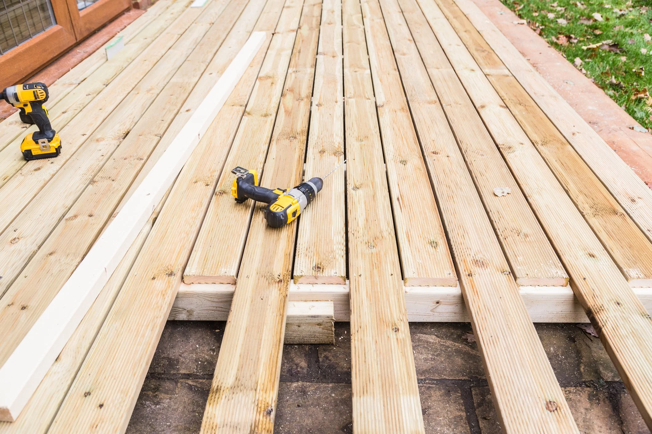  Wooden deck in construction with power drills and wooden planks on site.