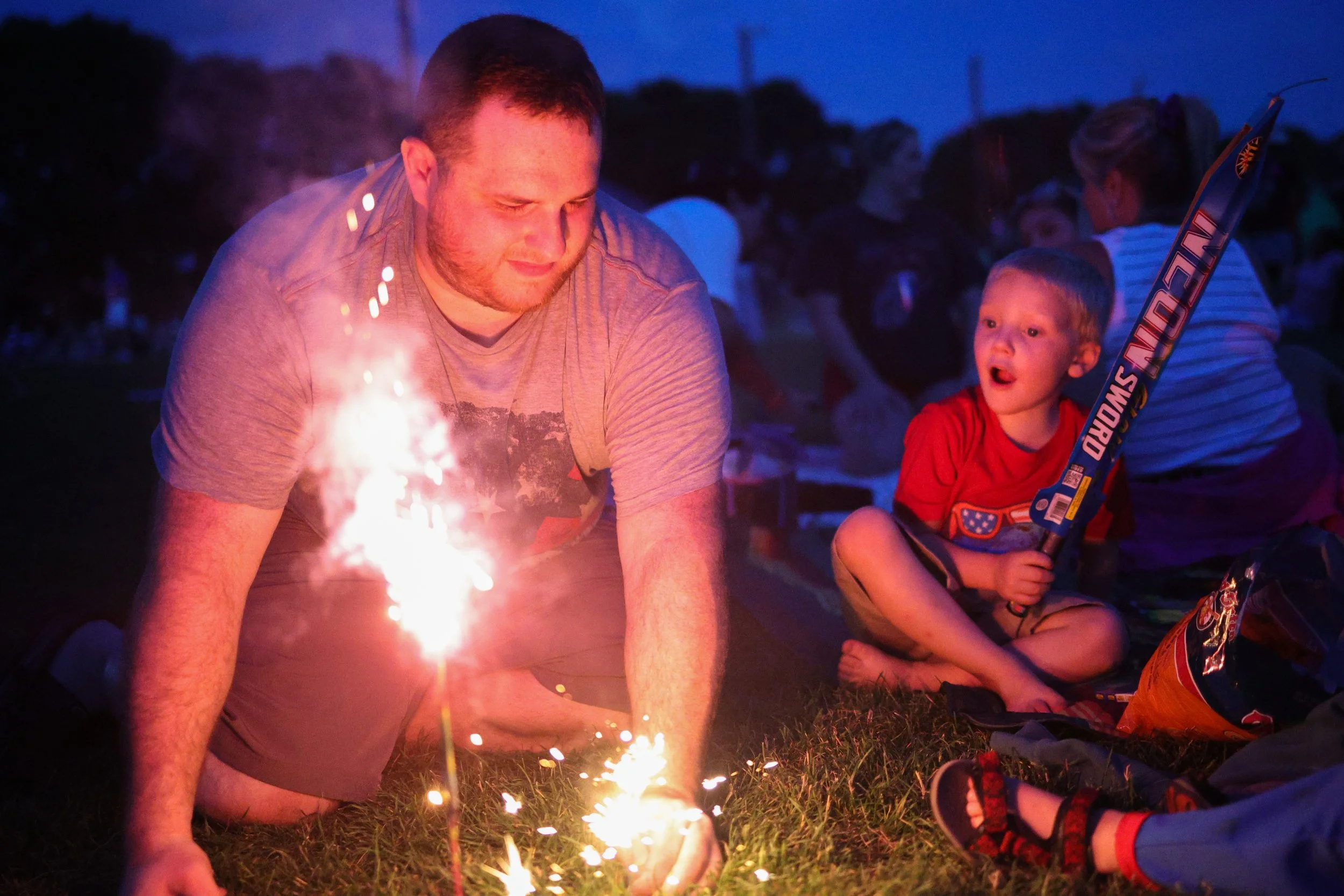 Wesley Naumann, 4, watches Ricky Sarran light a sparkler during Rochester's 4th Fest at Soldiers Field Park on Friday, July 4, 2025 in Rochester. (Post Bulletin)