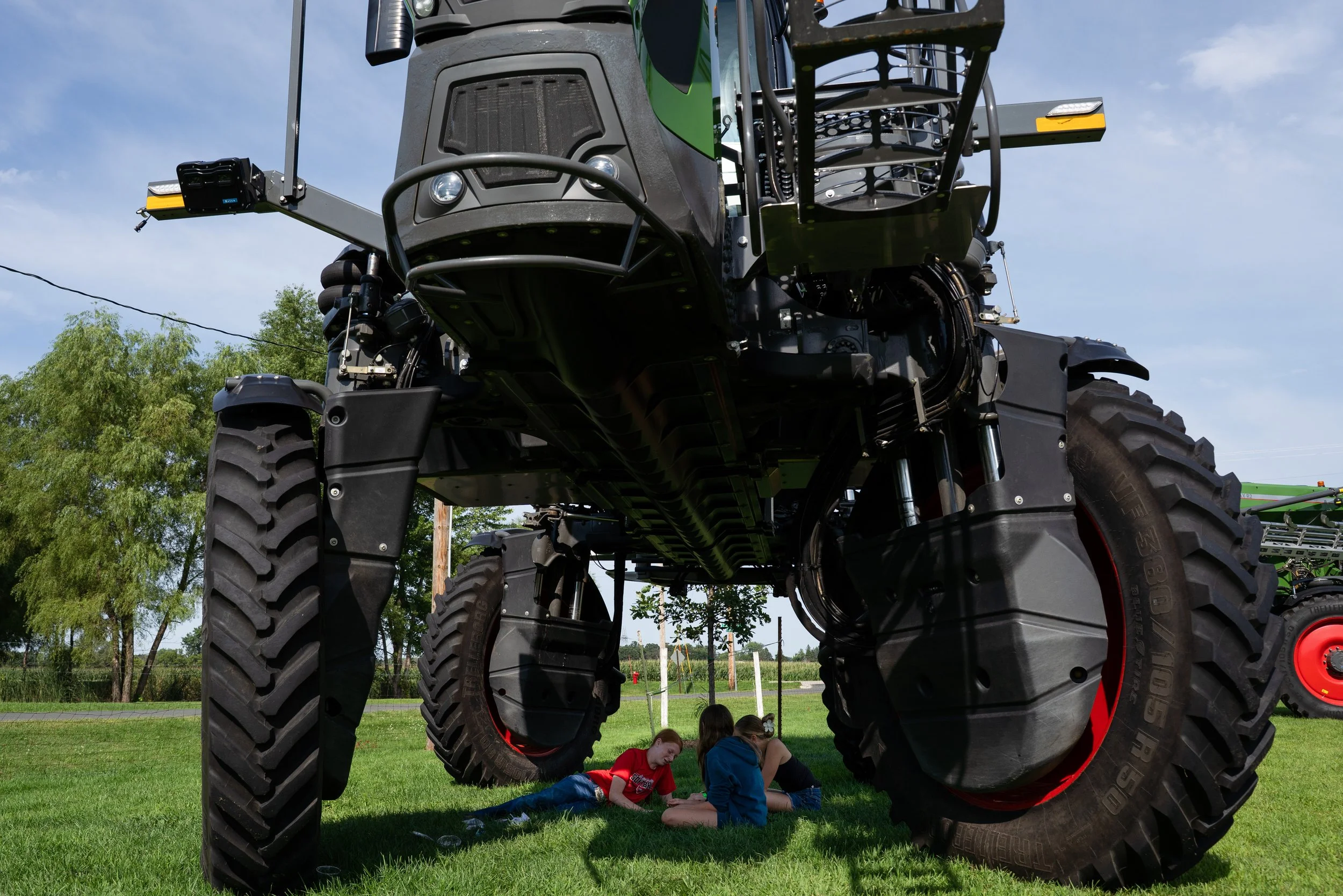 Hazel Lugmamn, Evy Lexvold and Abigail Sievers cool off in the shade under a large tractor at the Goodhue County Fair on Saturday, Aug. 9, 2025 in Zumbrota. (Post Bulletin)