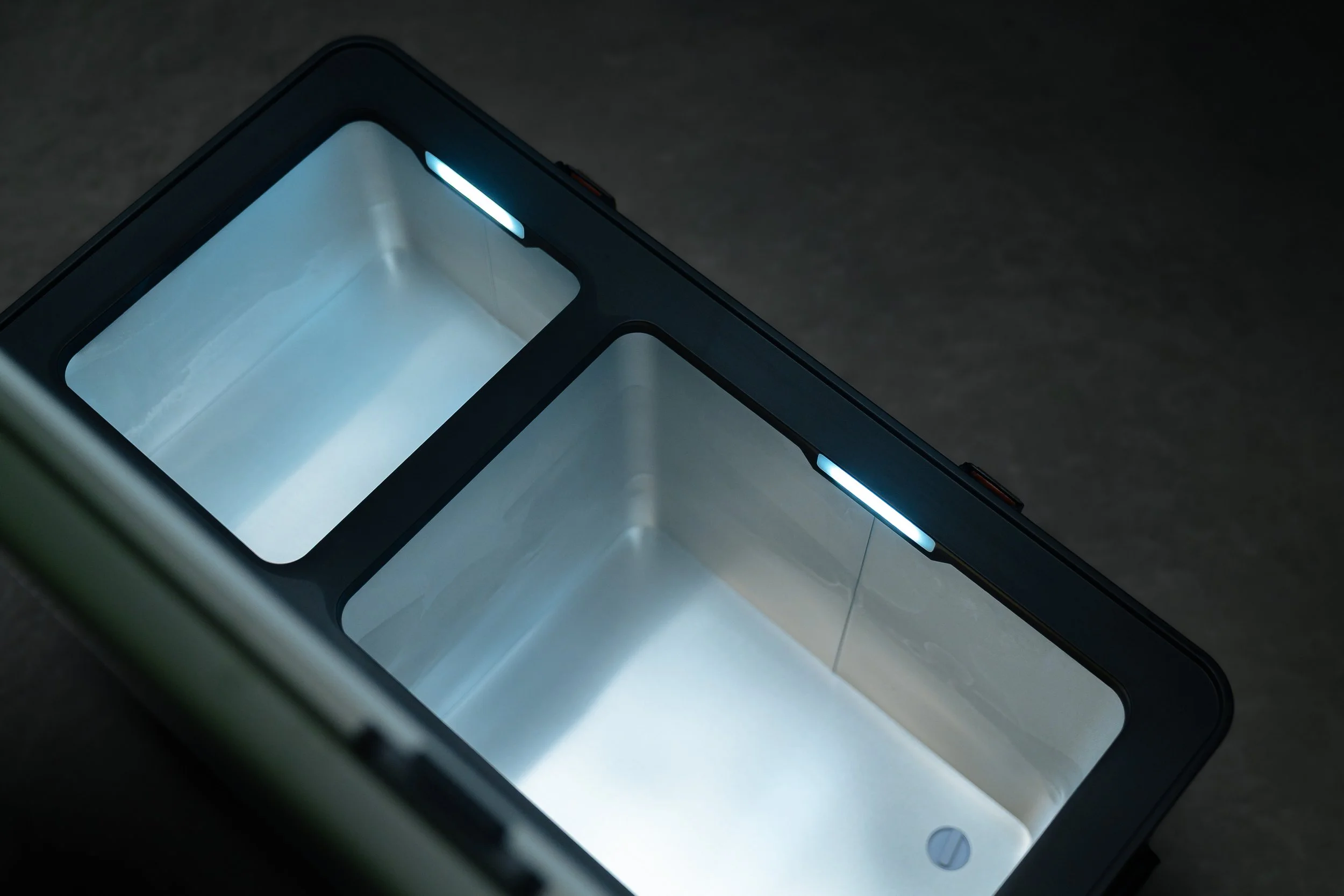 Close-up of a modern electronic device, possibly a smartphone or tablet, with a sleek black border and illuminated blue accents on a dark surface.