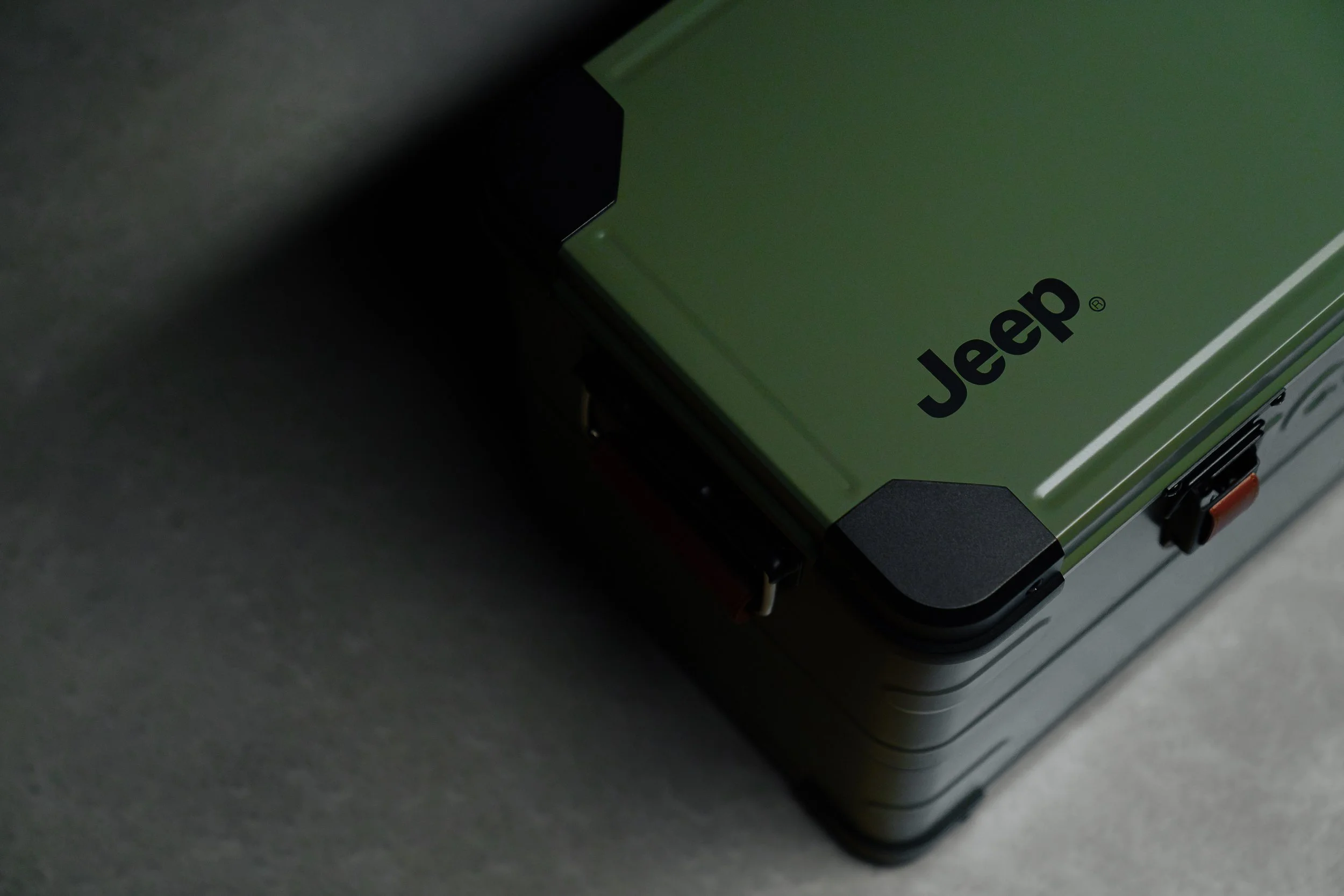 Close-up of a Jeep vehicle with the Jeep logo visible on the green part of the vehicle, taken in a dark setting.