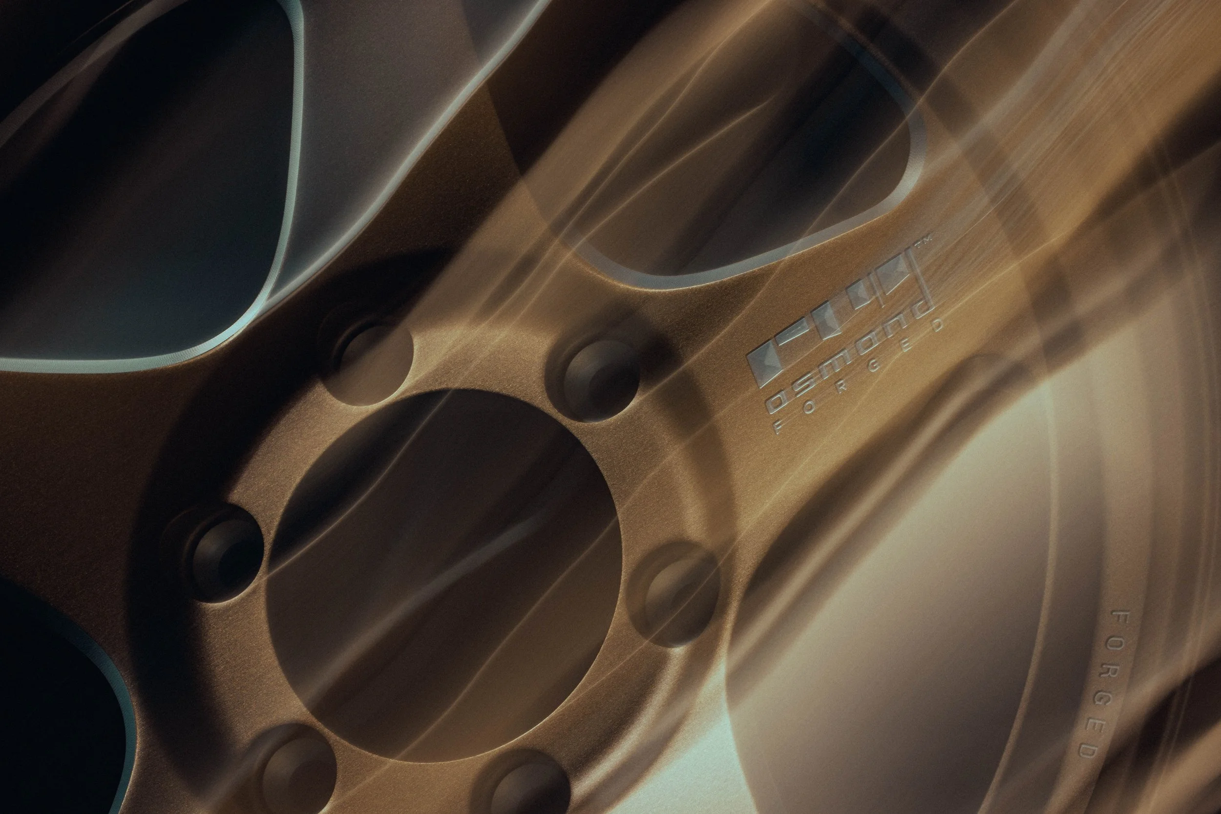 Close-up of a metallic object with the words 'Fusion Forge' engraved on it, and multiple circular indentations or drill holes.